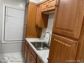 Kitchen with brown cabinets, light countertops, and light marble finish floors Kitchen with brown cabinets, light countertops, and light marble finish floors