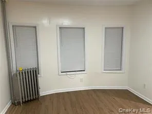 Spare room featuring radiator and dark wood finished floors Spare room featuring radiator and dark wood finished floors