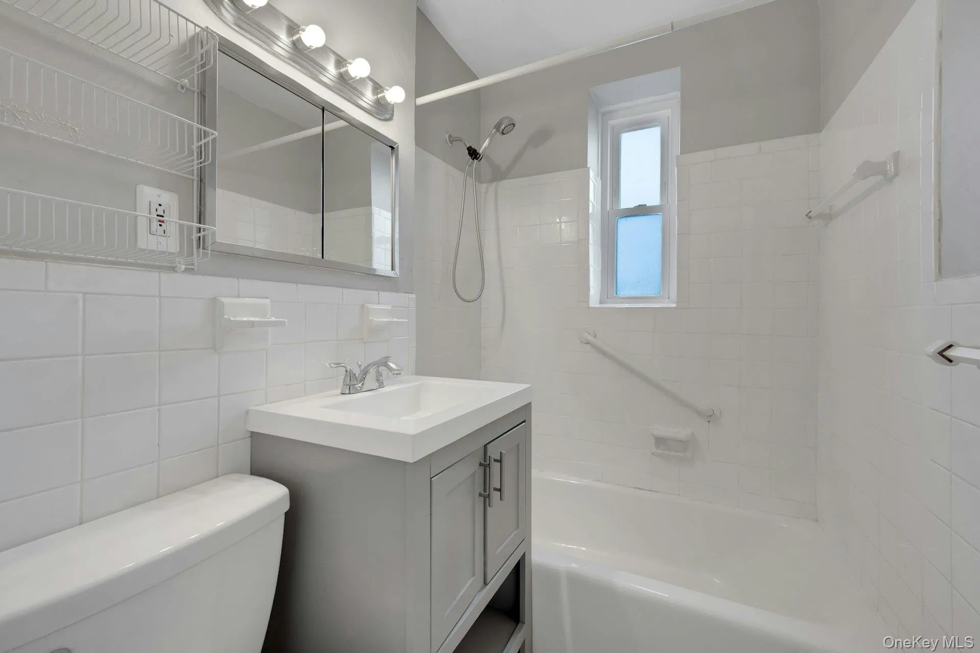 Full bathroom featuring vanity, shower / tub combination, and tile walls Full bathroom featuring vanity, shower / tub combination, and tile walls
