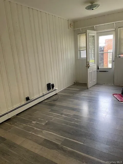 Spare room with a baseboard heating unit and dark wood-style flooring Spare room with a baseboard heating unit and dark wood-style flooring