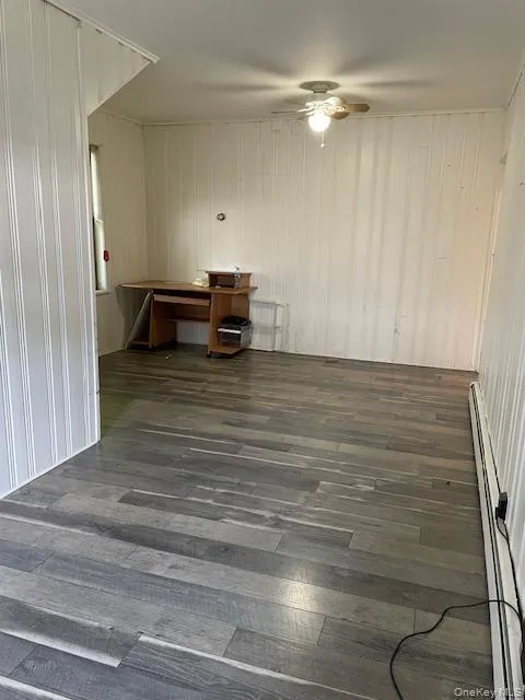 Unfurnished room featuring dark wood finished floors, a baseboard heating unit, and a ceiling fan Unfurnished room featuring dark wood finished floors, a baseboard heating unit, and a ceiling fan