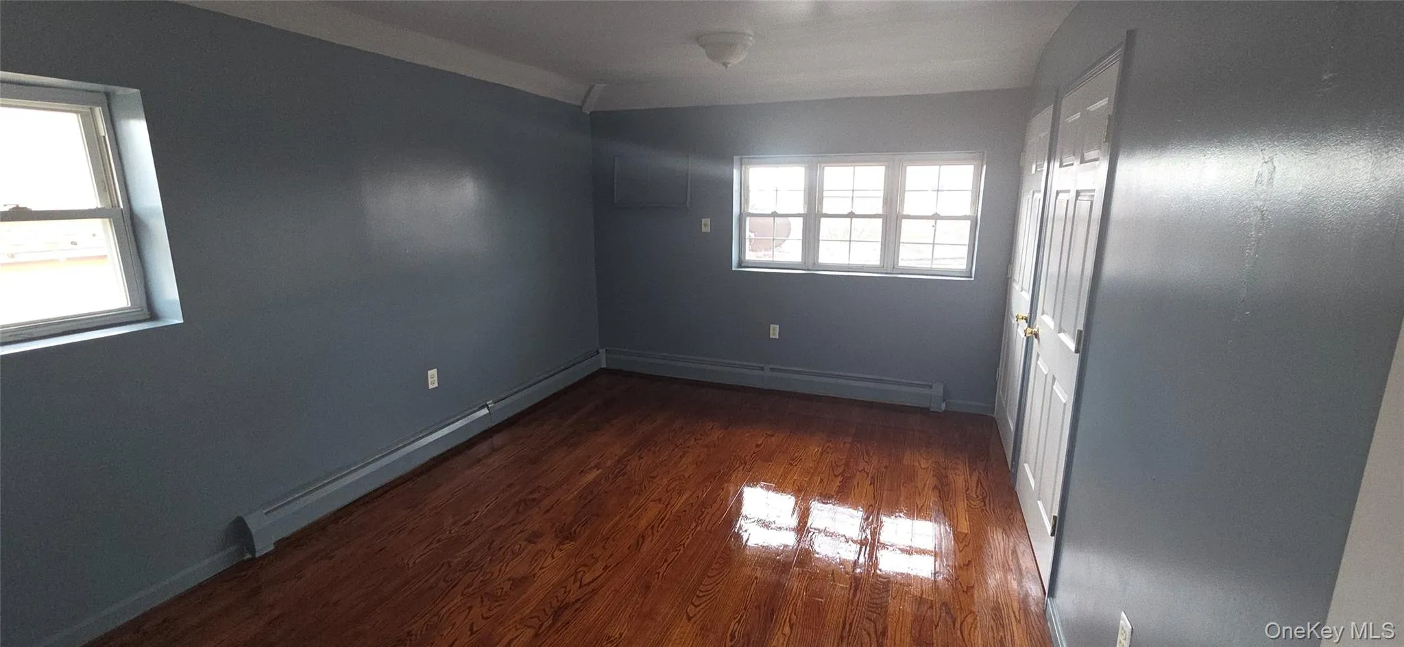 Spare room featuring a baseboard radiator and dark wood-style floors Spare room featuring a baseboard radiator and dark wood-style floors