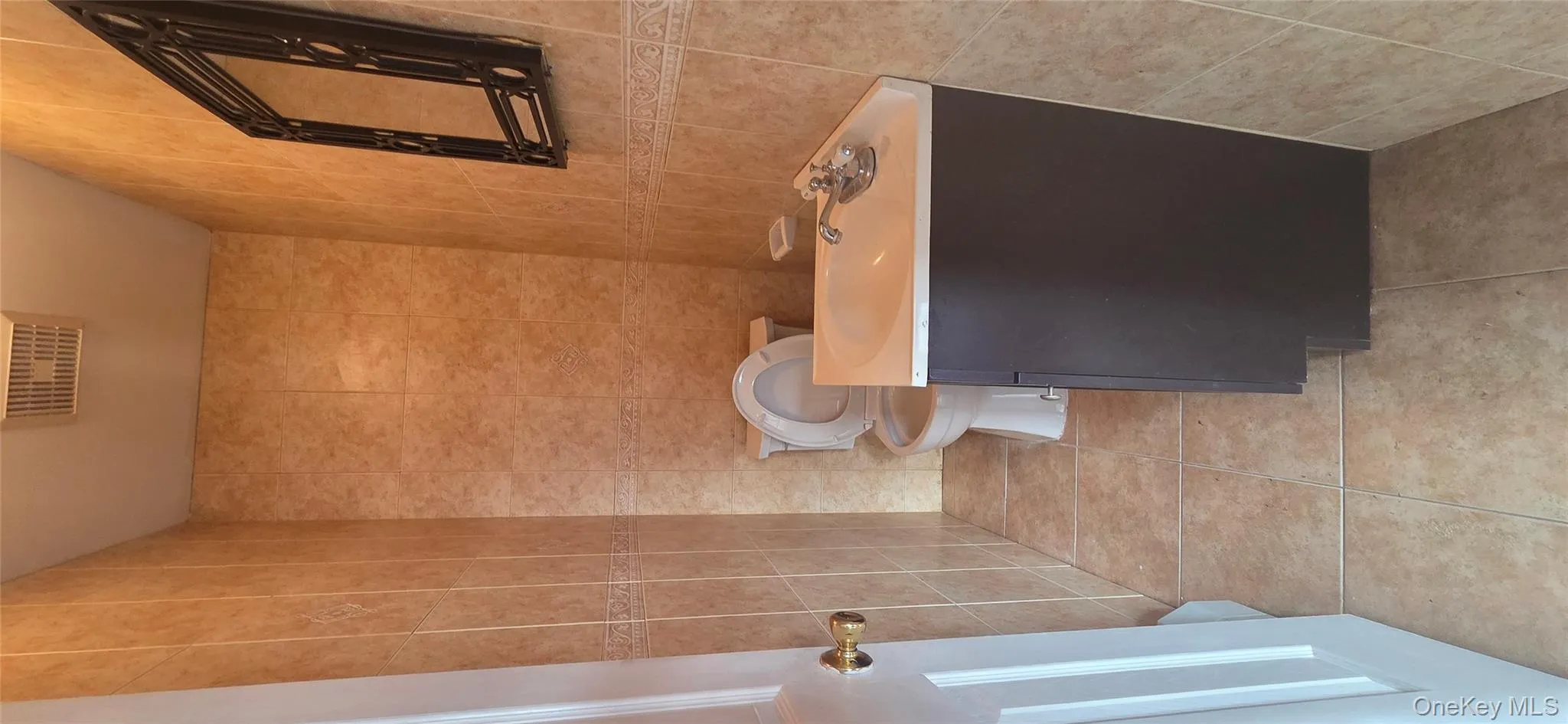 Bathroom featuring vanity, tile walls, and light tile patterned floors Bathroom featuring vanity, tile walls, and light tile patterned floors