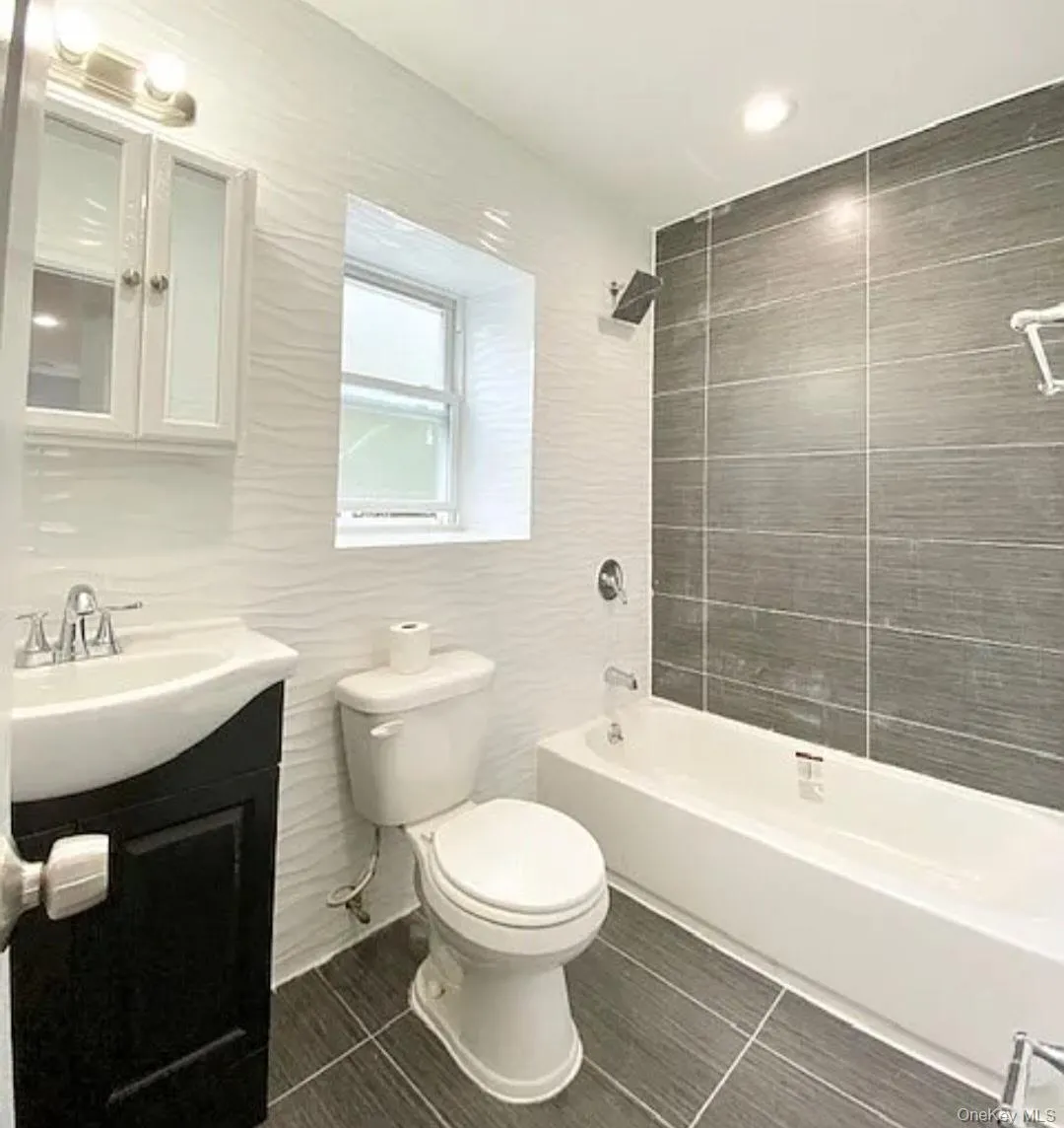 Full bathroom featuring washtub / shower combination, vanity, and recessed lighting Full bathroom featuring washtub / shower combination, vanity, and recessed lighting