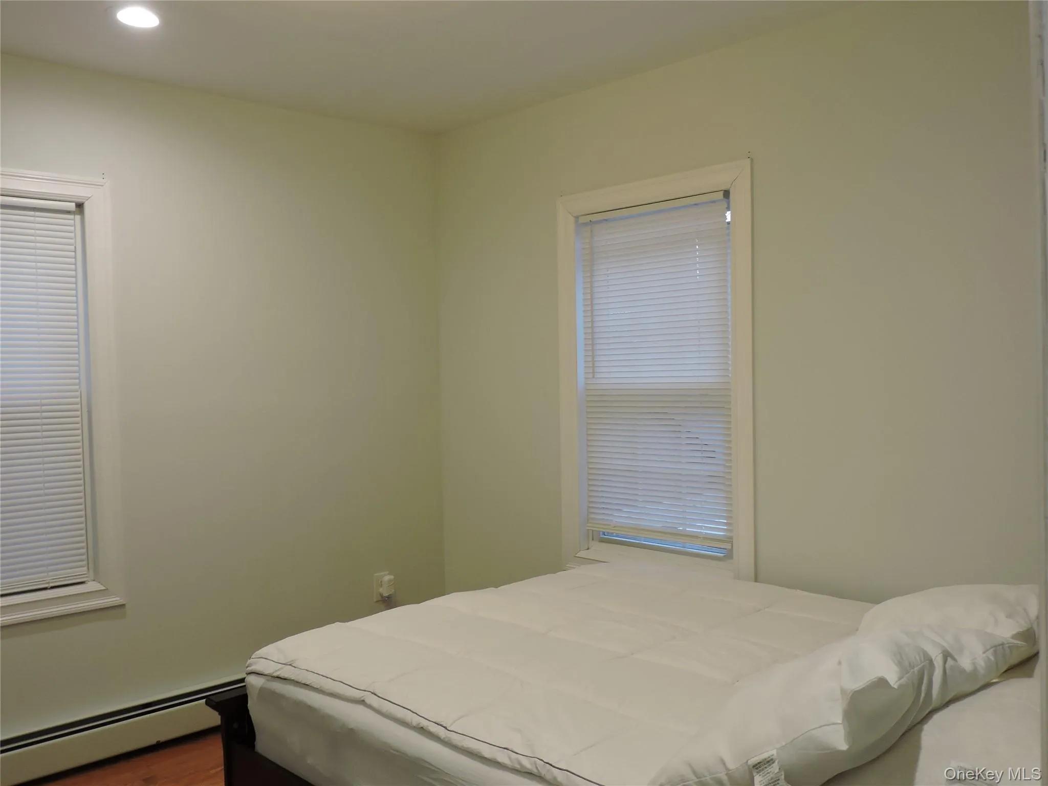 Bedroom featuring baseboard heating, recessed lighting, and wood finished floors Bedroom featuring baseboard heating, recessed lighting, and wood finished floors
