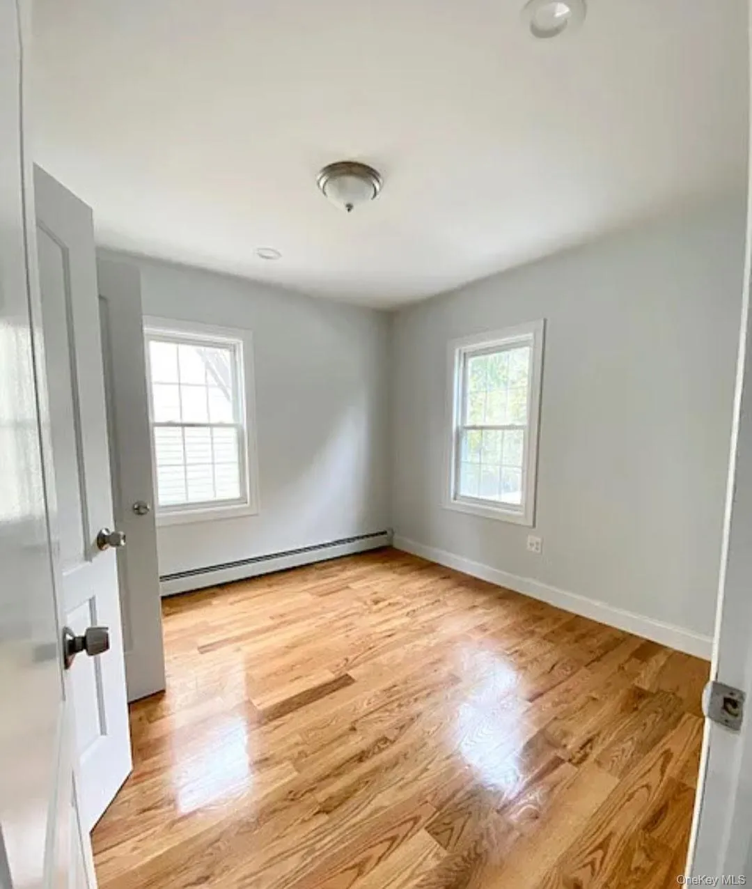 Spare room featuring light wood-type flooring and a baseboard radiator Spare room featuring light wood-type flooring and a baseboard radiator