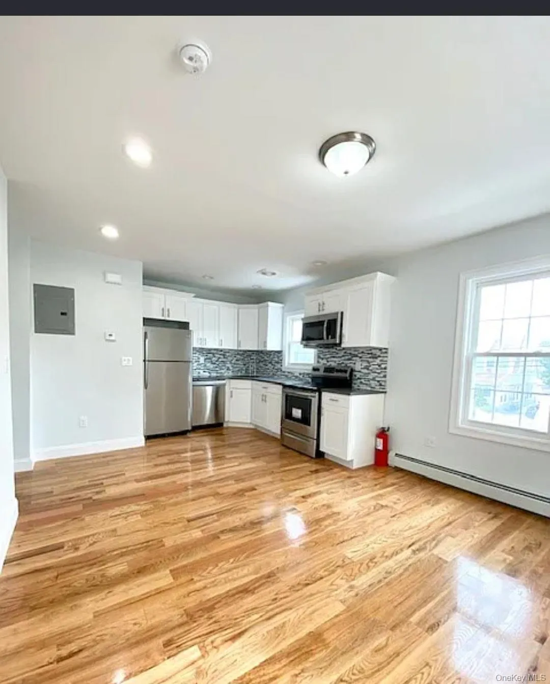Kitchen with white cabinets, stainless steel appliances, plenty of natural light, a baseboard heating unit, and recessed lighting Kitchen with white cabinets, stainless steel appliances, plenty of natural light, a baseboard heating unit, and recessed lighting