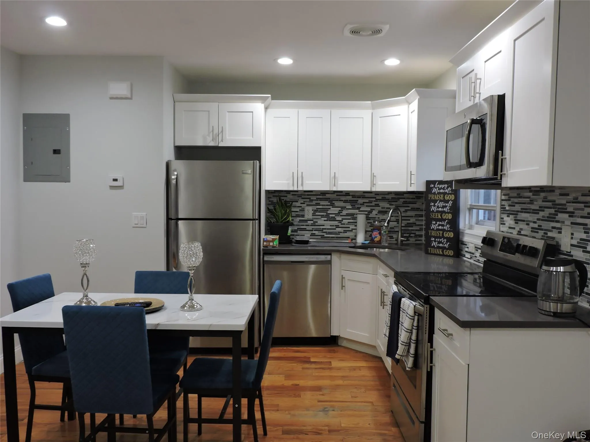 Kitchen featuring appliances with stainless steel finishes, light wood-type flooring, electric panel, white cabinets, and recessed lighting Kitchen featuring appliances with stainless steel finishes, light wood-type flooring, electric panel, white cabinets, and recessed lighting