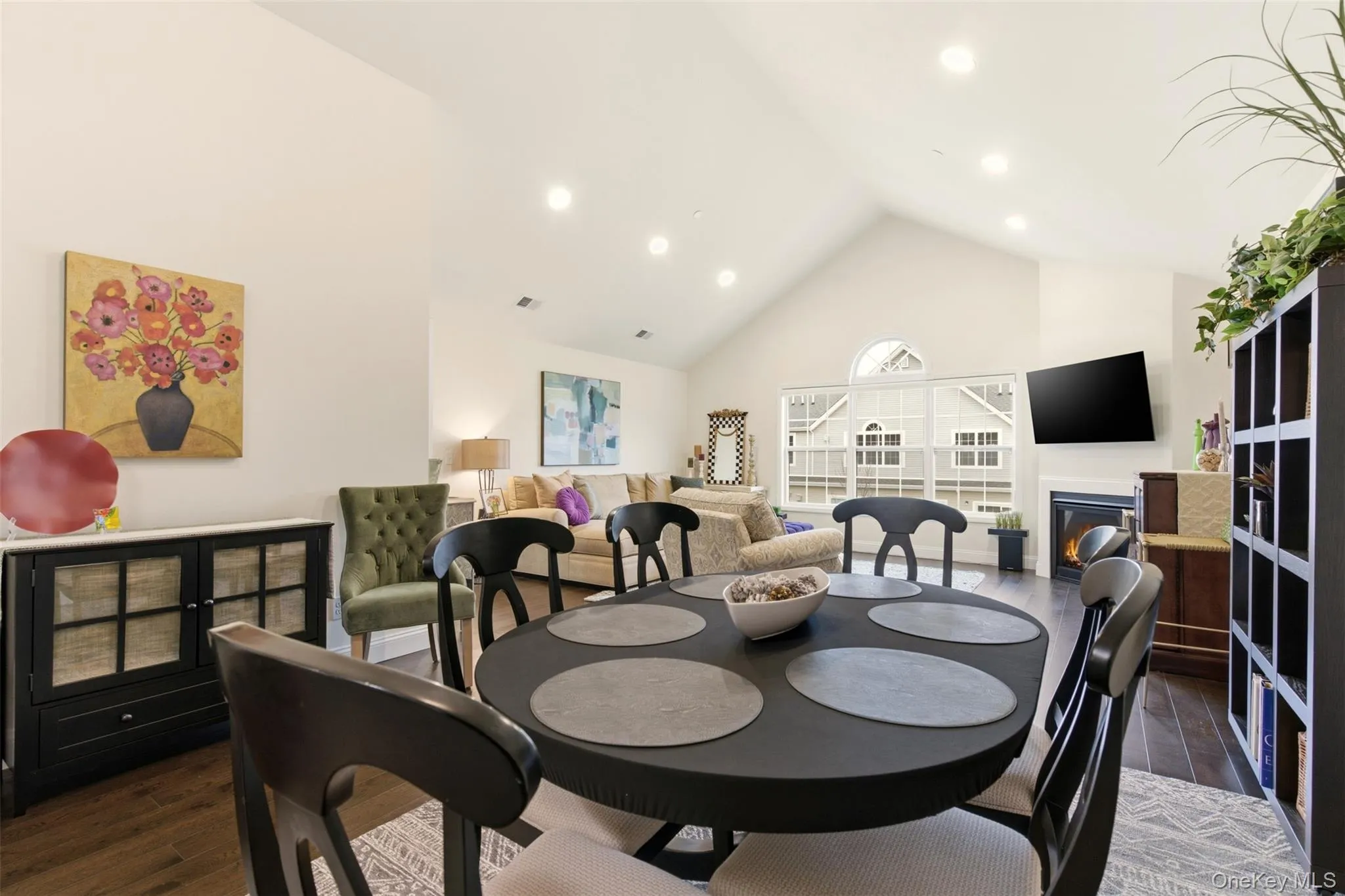 Dining room with a glass covered fireplace, dark wood-type flooring, high vaulted ceiling, and recessed lighting Dining room with a glass covered fireplace, dark wood-type flooring, high vaulted ceiling, and recessed lighting