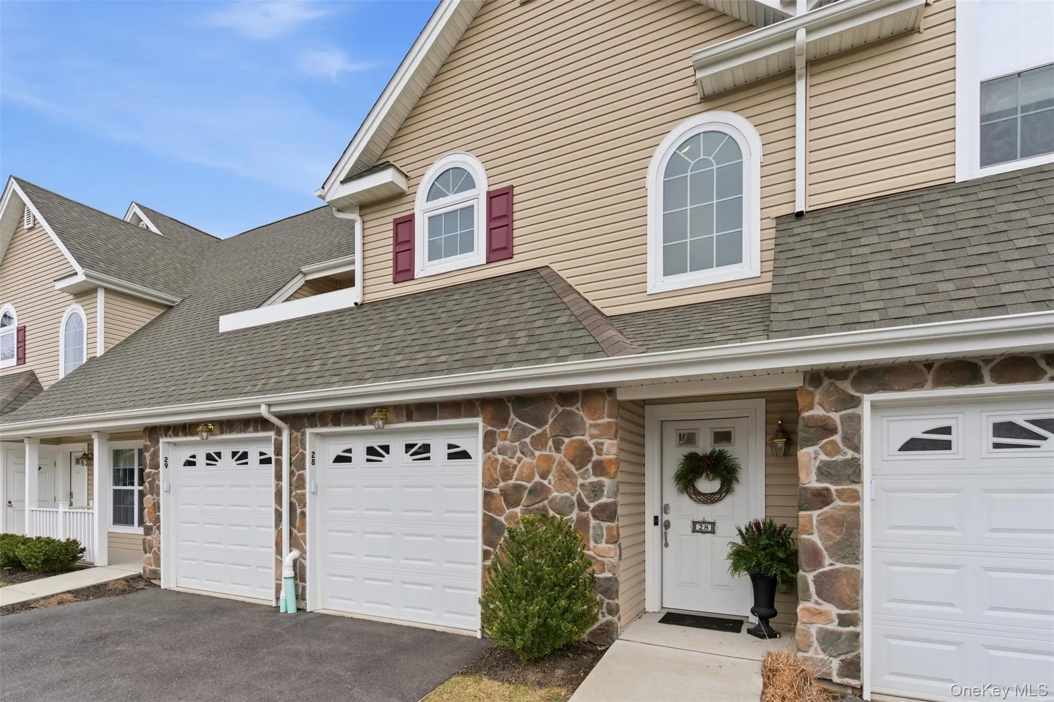 Traditional-style home with stone siding, driveway, and a shingled roof Traditional-style home with stone siding, driveway, and a shingled roof
