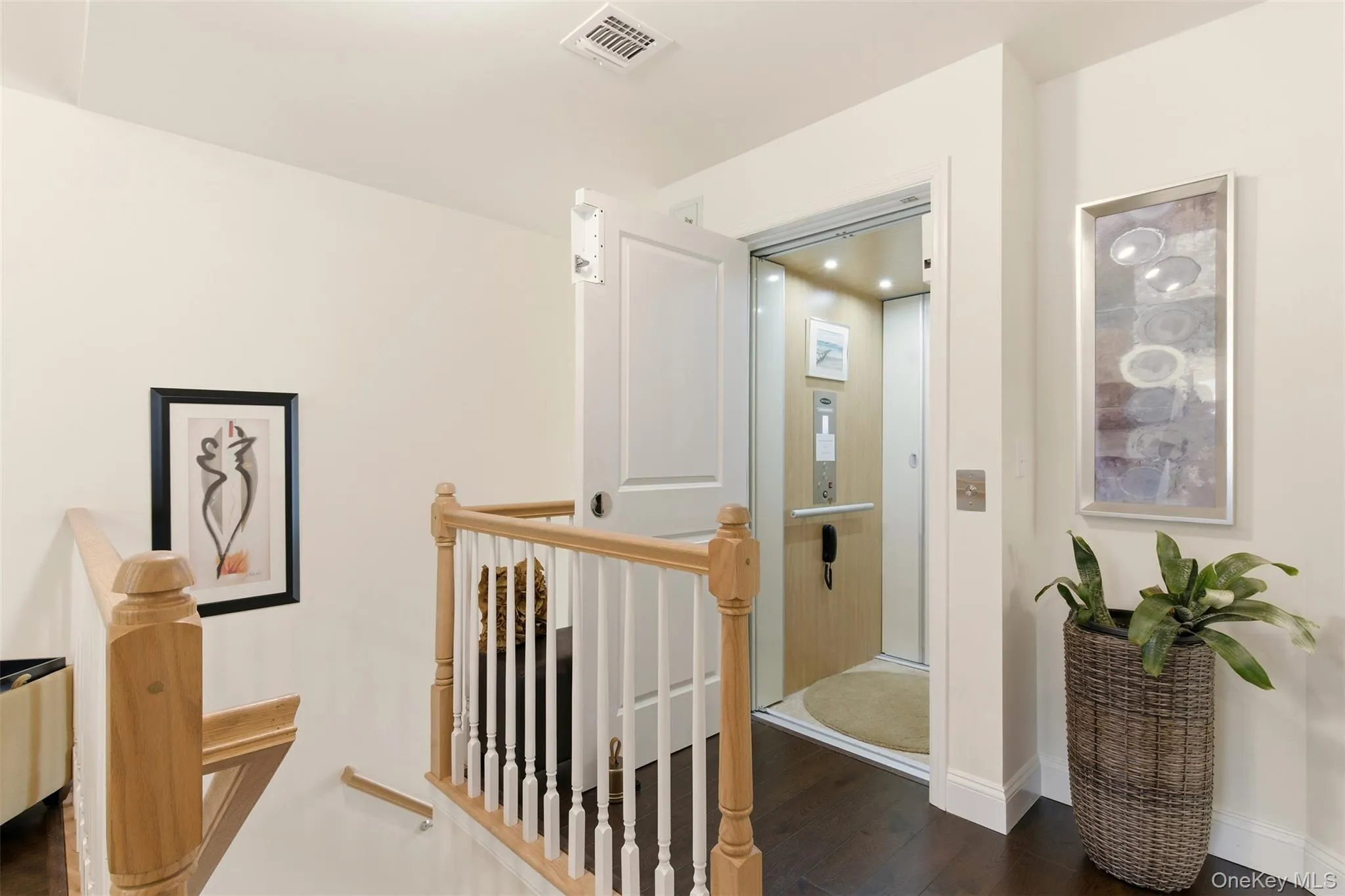 Hallway with an upstairs landing, dark wood-type flooring, and elevator Hallway with an upstairs landing, dark wood-type flooring, and elevator