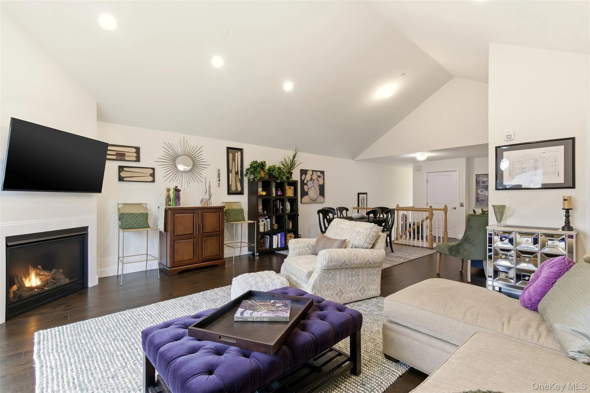 Living area with dark wood-type flooring, a glass covered fireplace, and high vaulted ceiling Living area with dark wood-type flooring, a glass covered fireplace, and high vaulted ceiling