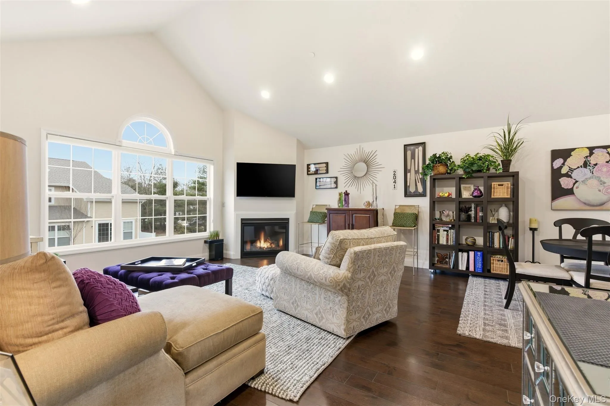 Living room with dark wood finished floors, a glass covered fireplace, recessed lighting, and high vaulted ceiling Living room with dark wood finished floors, a glass covered fireplace, recessed lighting, and high vaulted ceiling