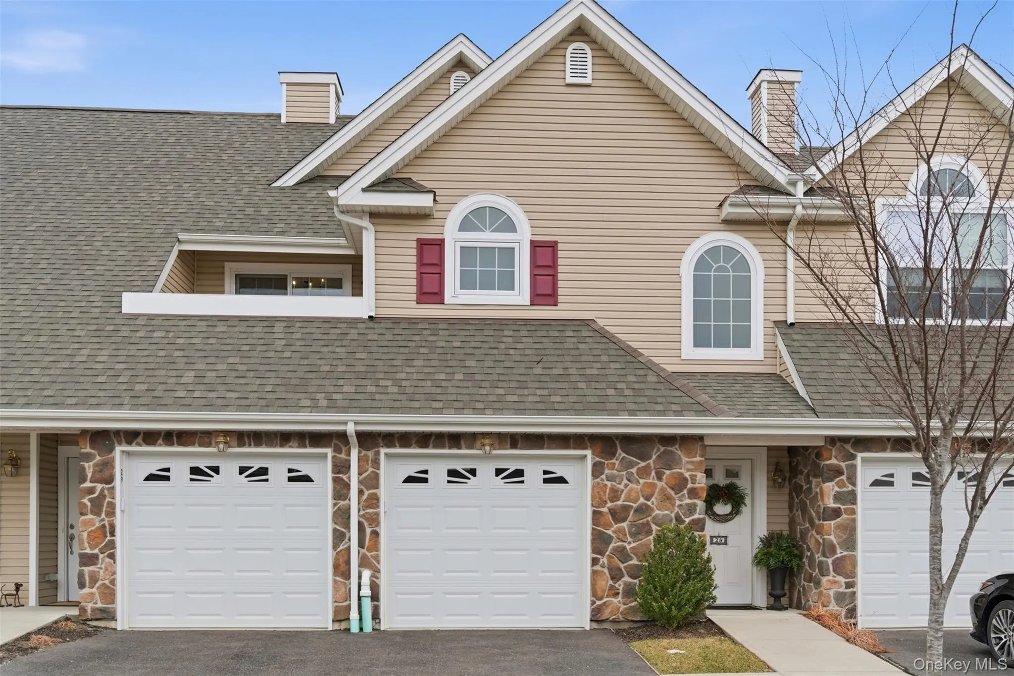 View of front of house featuring stone siding, a chimney, asphalt driveway, a shingled roof, and an attached garage View of front of house featuring stone siding, a chimney, asphalt driveway, a shingled roof, and an attached garage