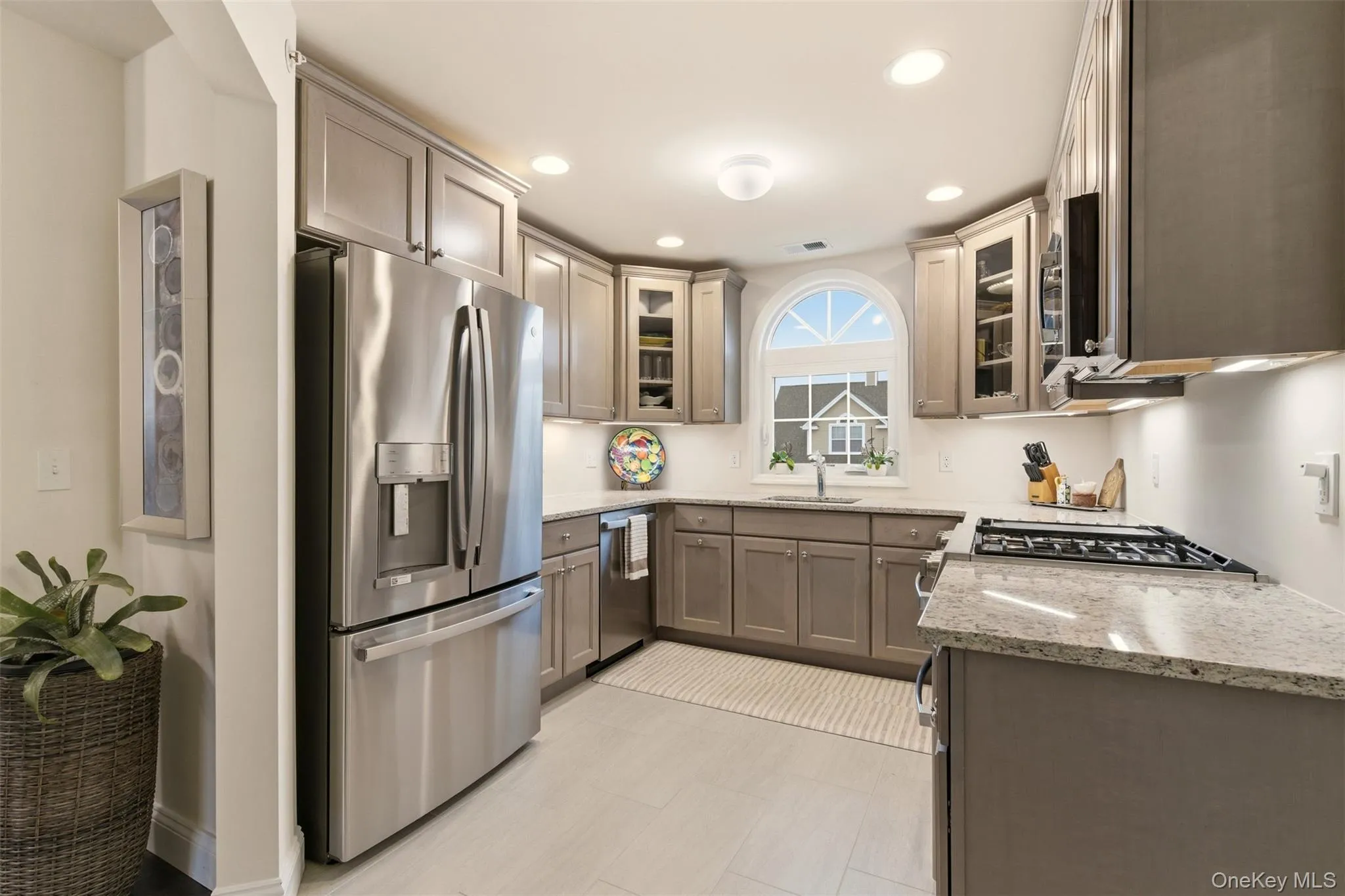 Kitchen featuring light stone countertops, appliances with stainless steel finishes, glass insert cabinets, and recessed lighting Kitchen featuring light stone countertops, appliances with stainless steel finishes, glass insert cabinets, and recessed lighting