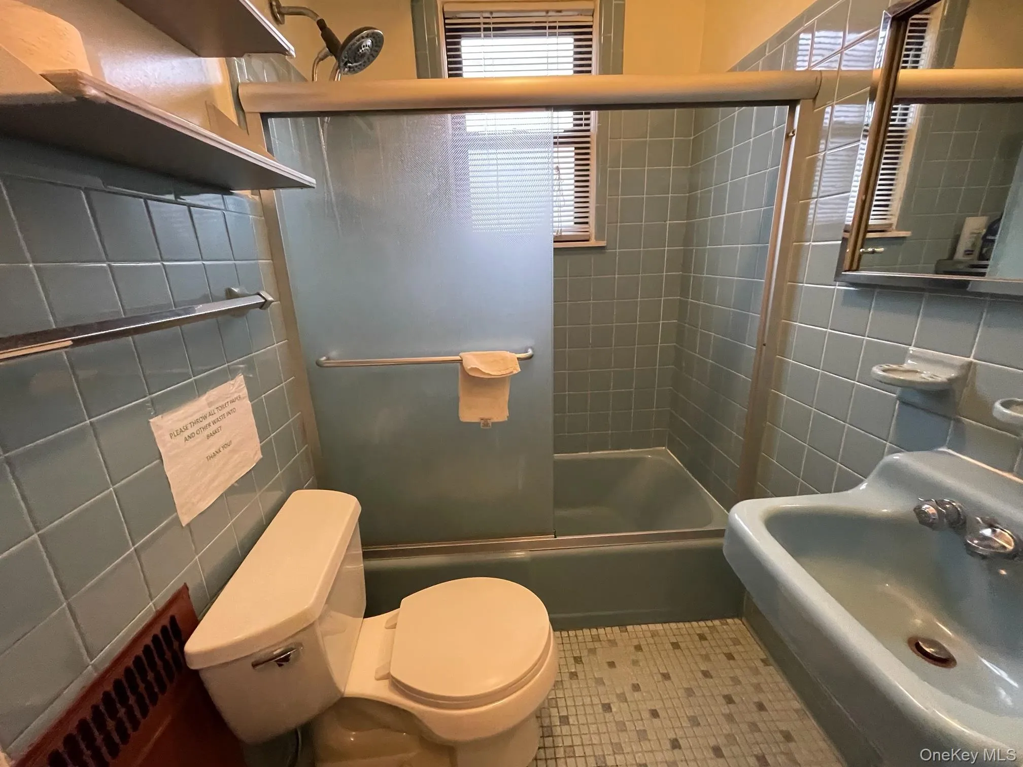 Bathroom with tile walls, bath / shower combo with glass door, and tile patterned floors Bathroom with tile walls, bath / shower combo with glass door, and tile patterned floors