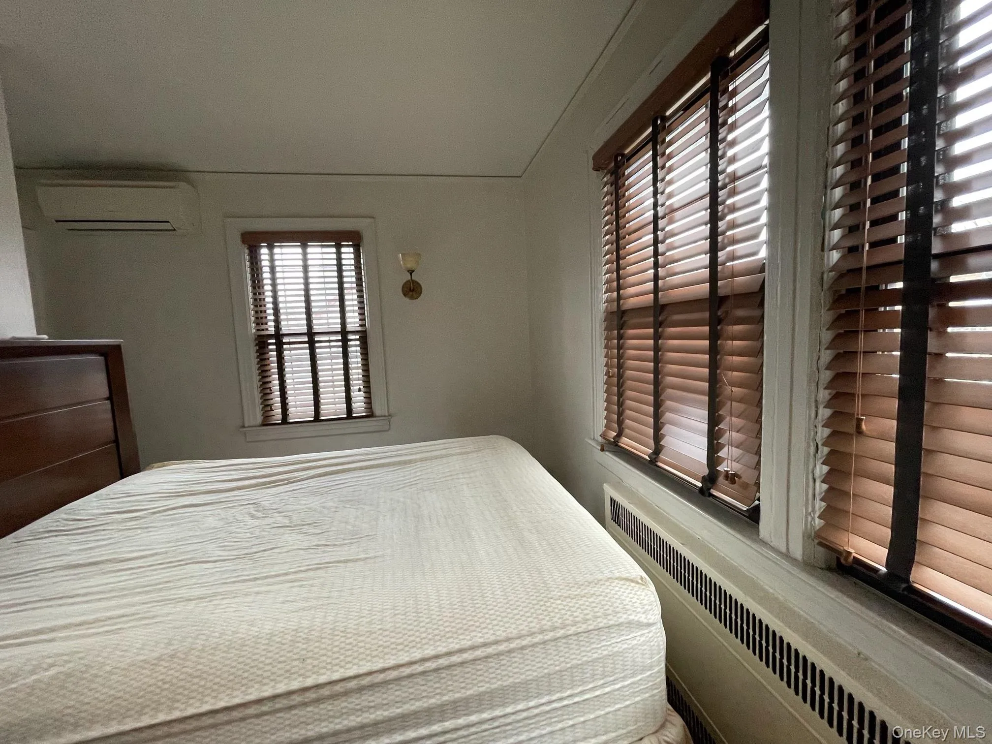 Bedroom featuring radiator and an AC wall unit Bedroom featuring radiator and an AC wall unit