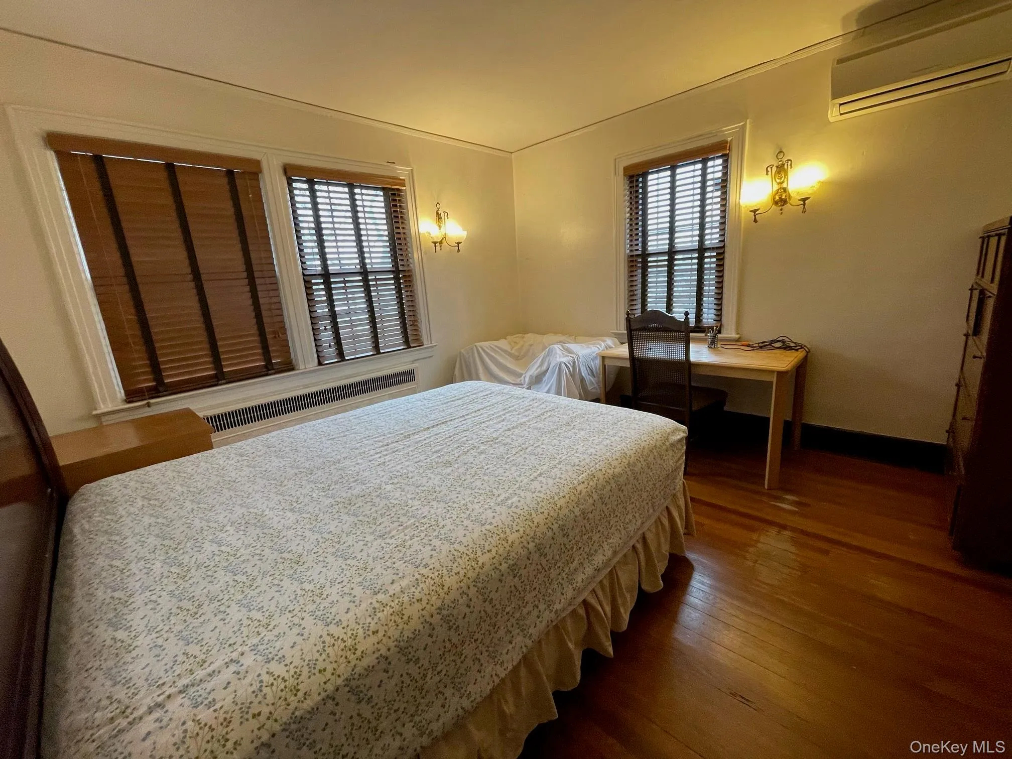 Bedroom with an AC wall unit, multiple windows, and dark wood-style floors Bedroom with an AC wall unit, multiple windows, and dark wood-style floors