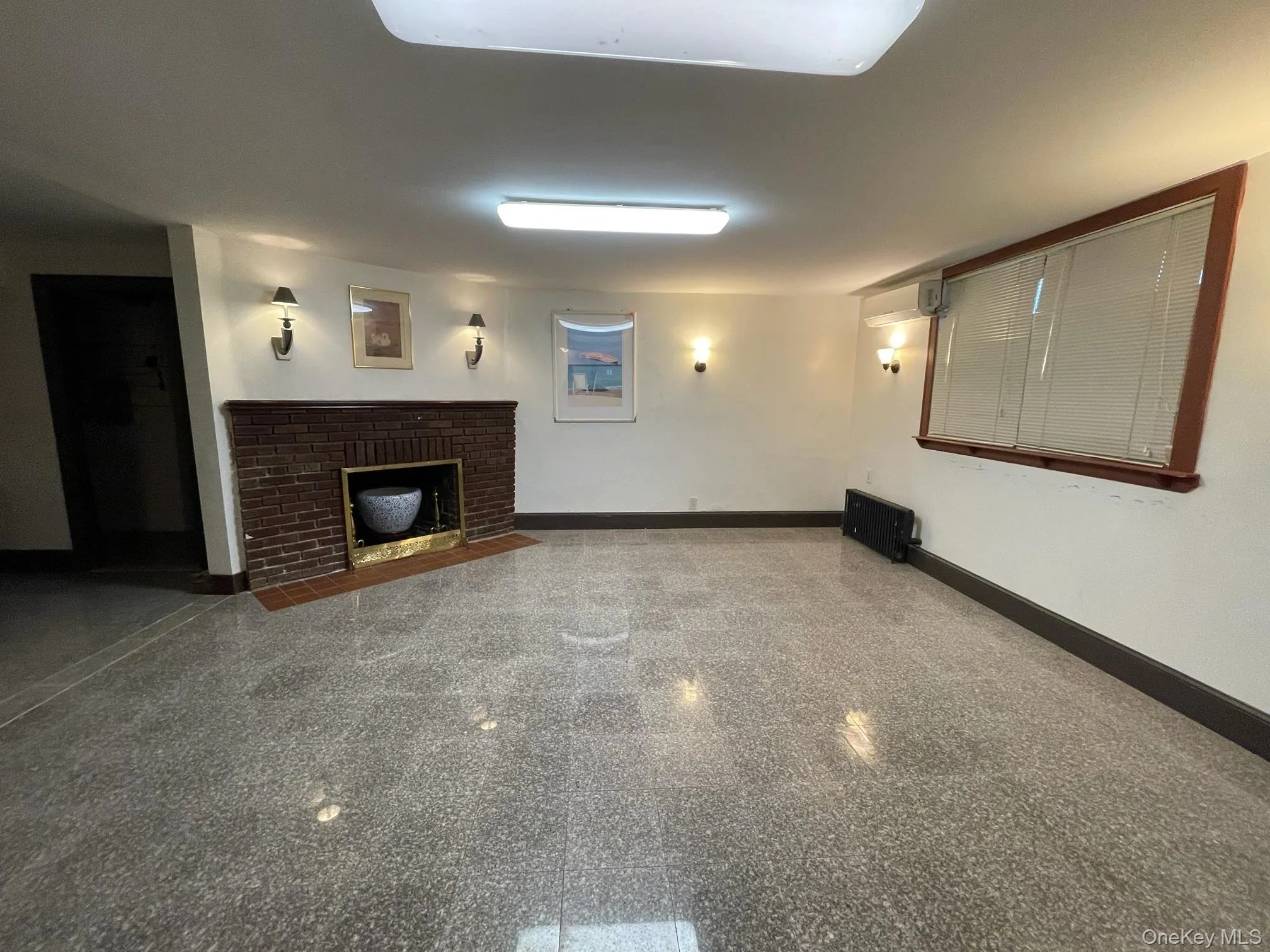 Unfurnished living room featuring a fireplace and granite tiled floors Unfurnished living room featuring a fireplace and granite tiled floors