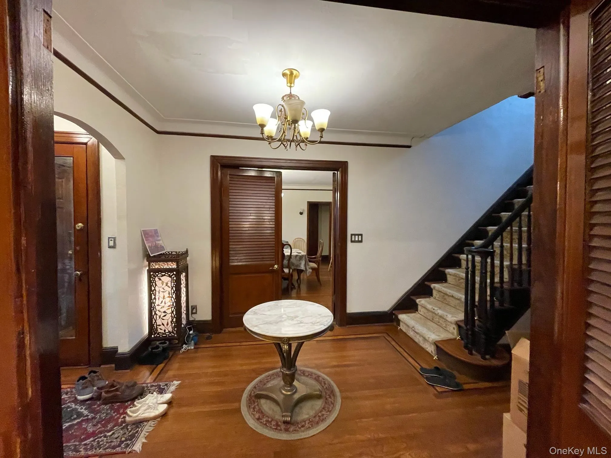 Entryway featuring arched walkways, wood finished floors, crown molding, a chandelier, and stairway Entryway featuring arched walkways, wood finished floors, crown molding, a chandelier, and stairway