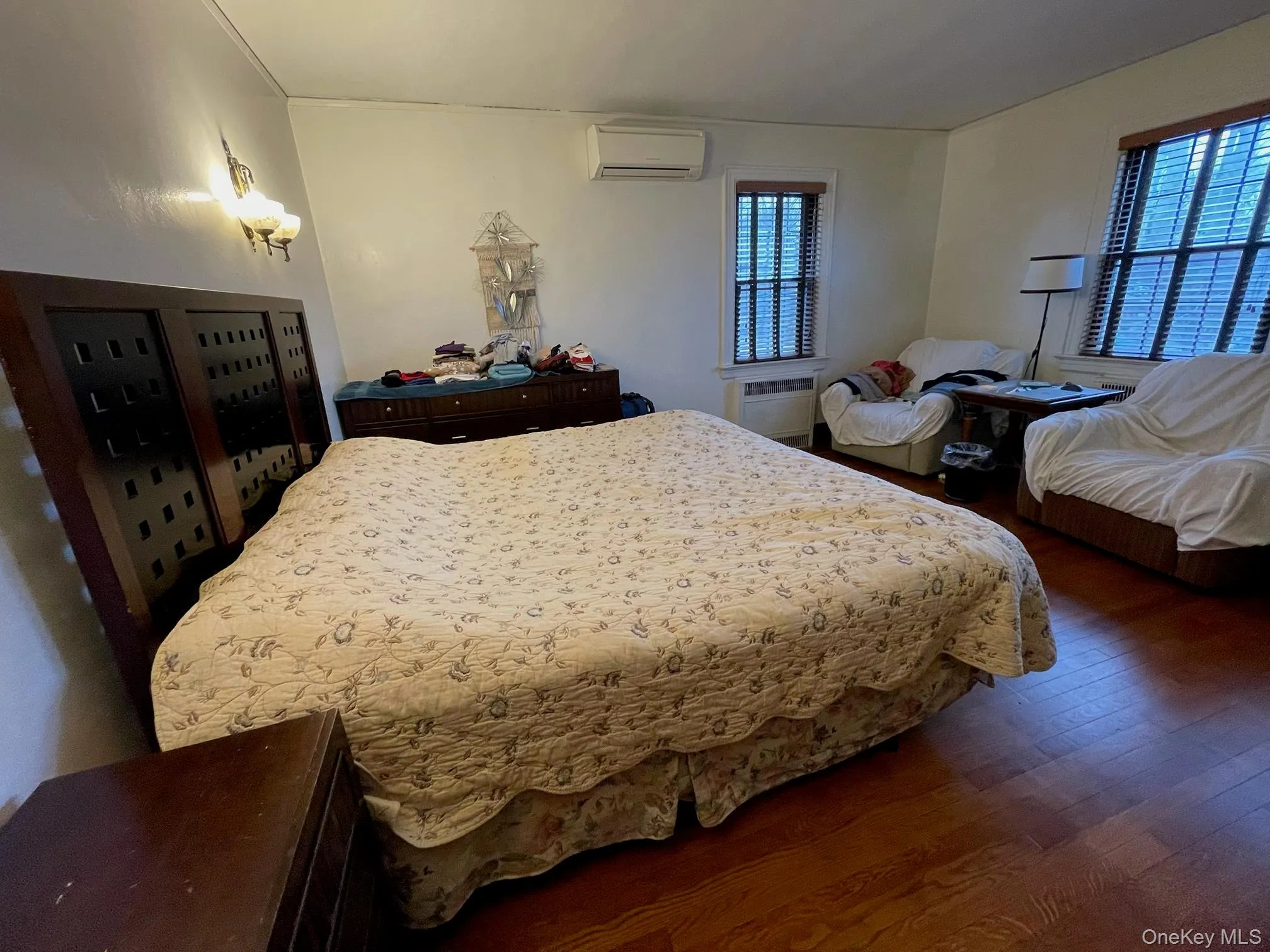 Bedroom featuring wood finished floors and a wall mounted air conditioner Bedroom featuring wood finished floors and a wall mounted air conditioner
