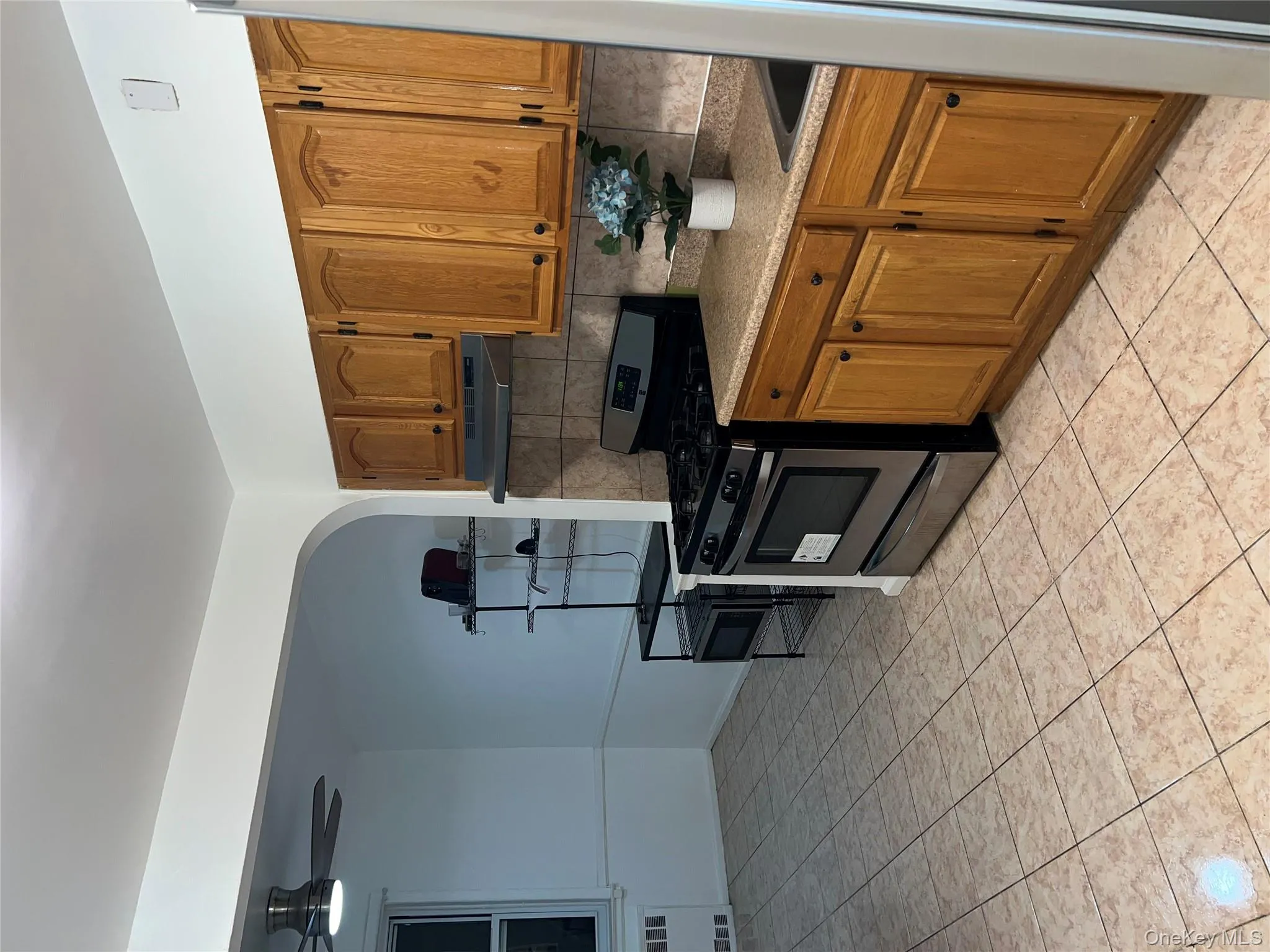 Kitchen with range, brown cabinetry, tasteful backsplash, and a ceiling fan Kitchen with range, brown cabinetry, tasteful backsplash, and a ceiling fan