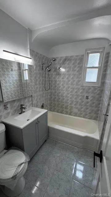 Full bathroom with vanity, shower / tub combination, tile walls, and plenty of natural light Full bathroom with vanity, shower / tub combination, tile walls, and plenty of natural light