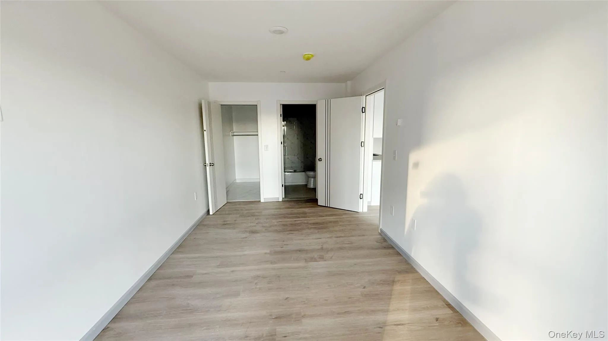 Unfurnished bedroom featuring light wood finished floors and connected bathroom Unfurnished bedroom featuring light wood finished floors and connected bathroom