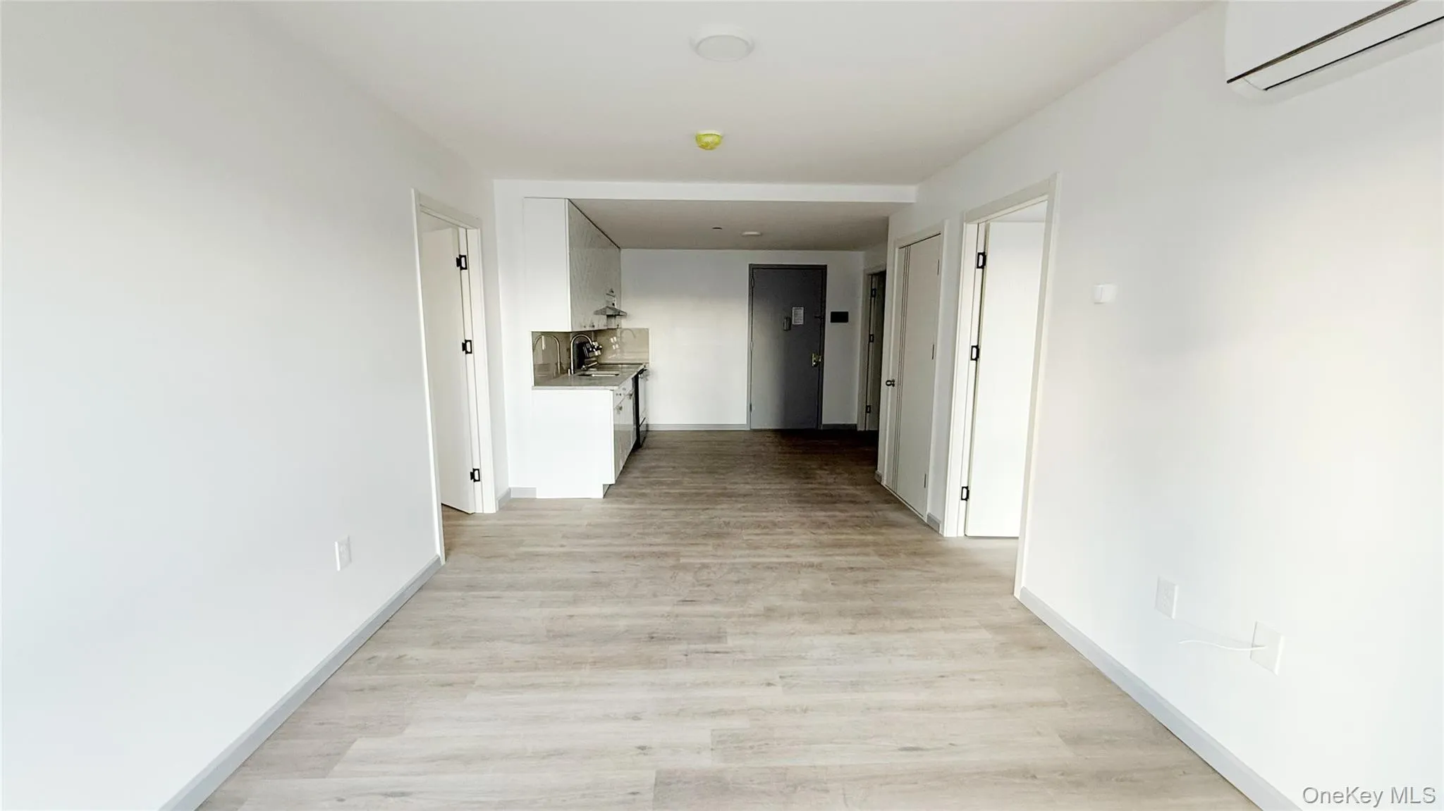 Corridor featuring an AC wall unit and light wood-type flooring Corridor featuring an AC wall unit and light wood-type flooring