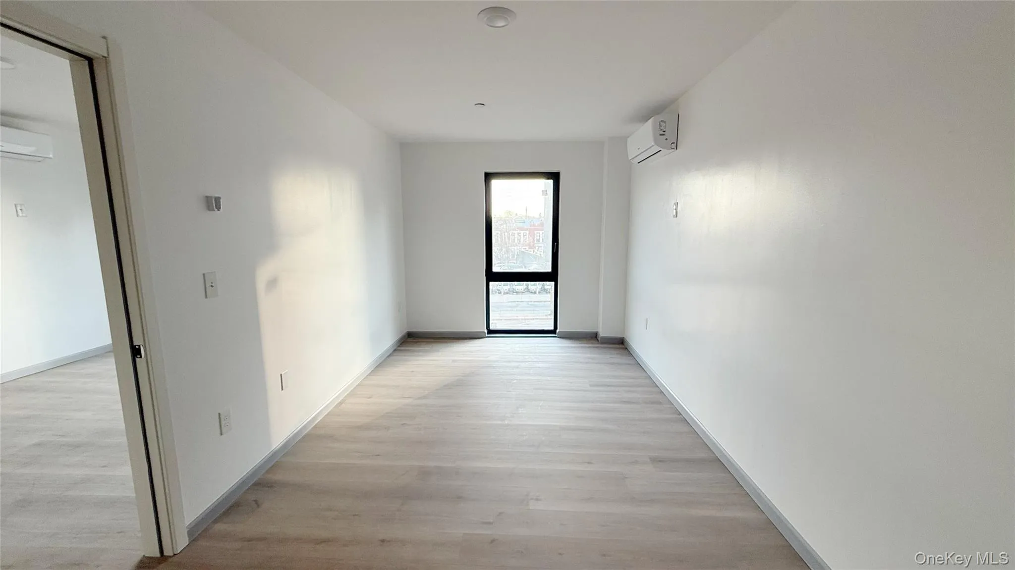 Hall featuring light wood-type flooring and a wall mounted air conditioner Hall featuring light wood-type flooring and a wall mounted air conditioner