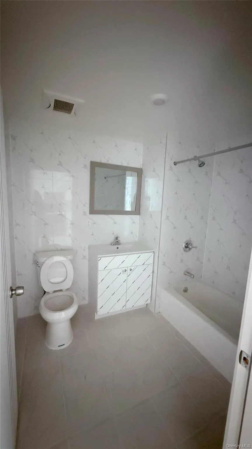 Bathroom featuring shower / bathtub combination, vanity, and tile walls Bathroom featuring shower / bathtub combination, vanity, and tile walls