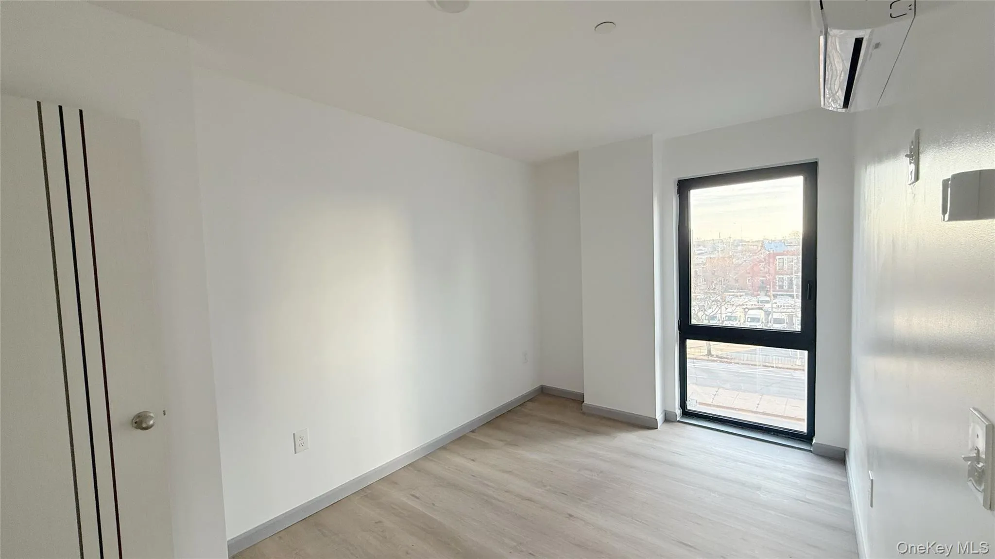 Unfurnished room featuring a wall mounted air conditioner and light wood-type flooring Unfurnished room featuring a wall mounted air conditioner and light wood-type flooring