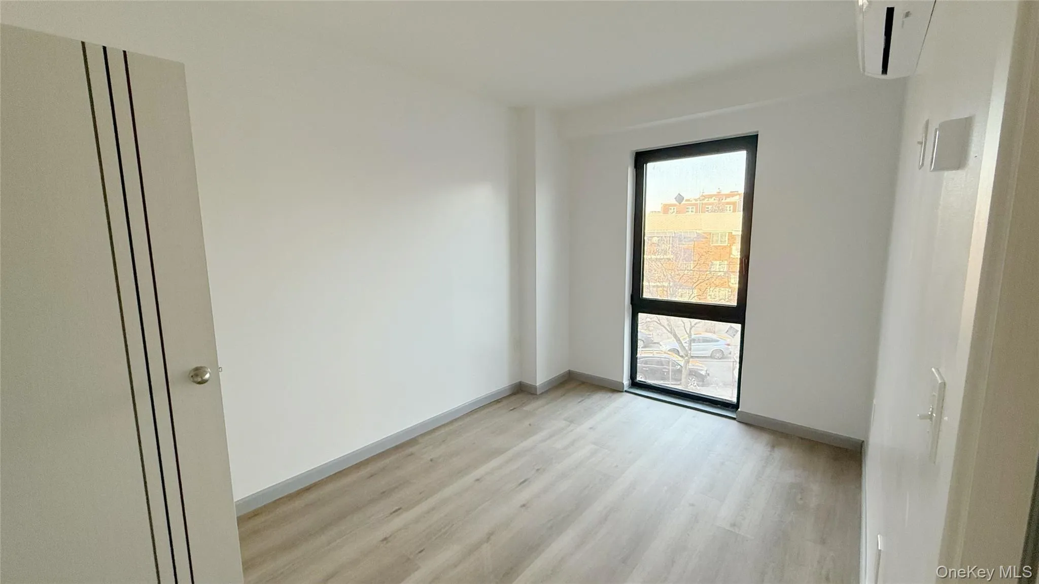 Empty room featuring a wall unit AC and light wood-type flooring Empty room featuring a wall unit AC and light wood-type flooring