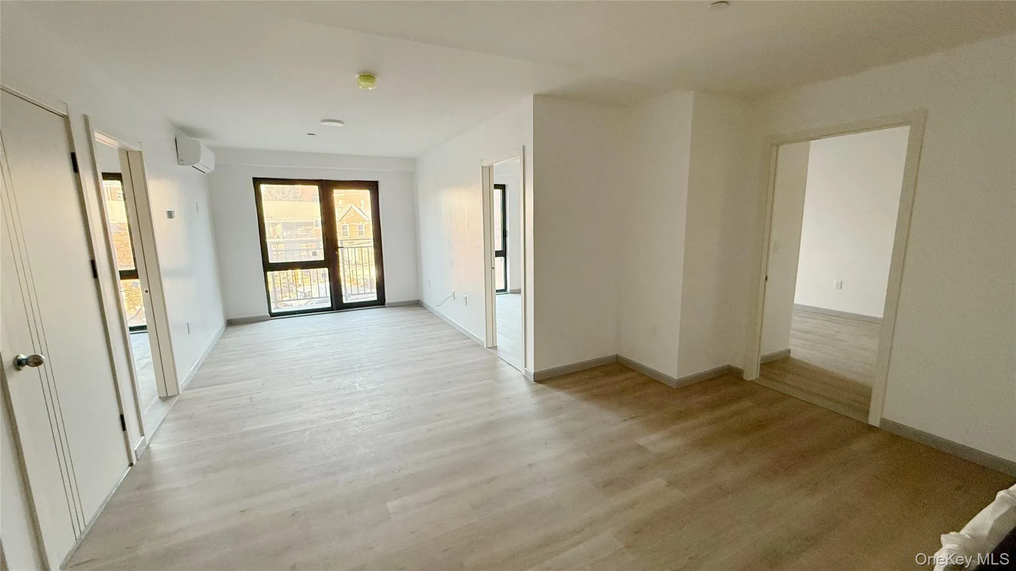 Corridor with light wood-style flooring and an AC wall unit Corridor with light wood-style flooring and an AC wall unit