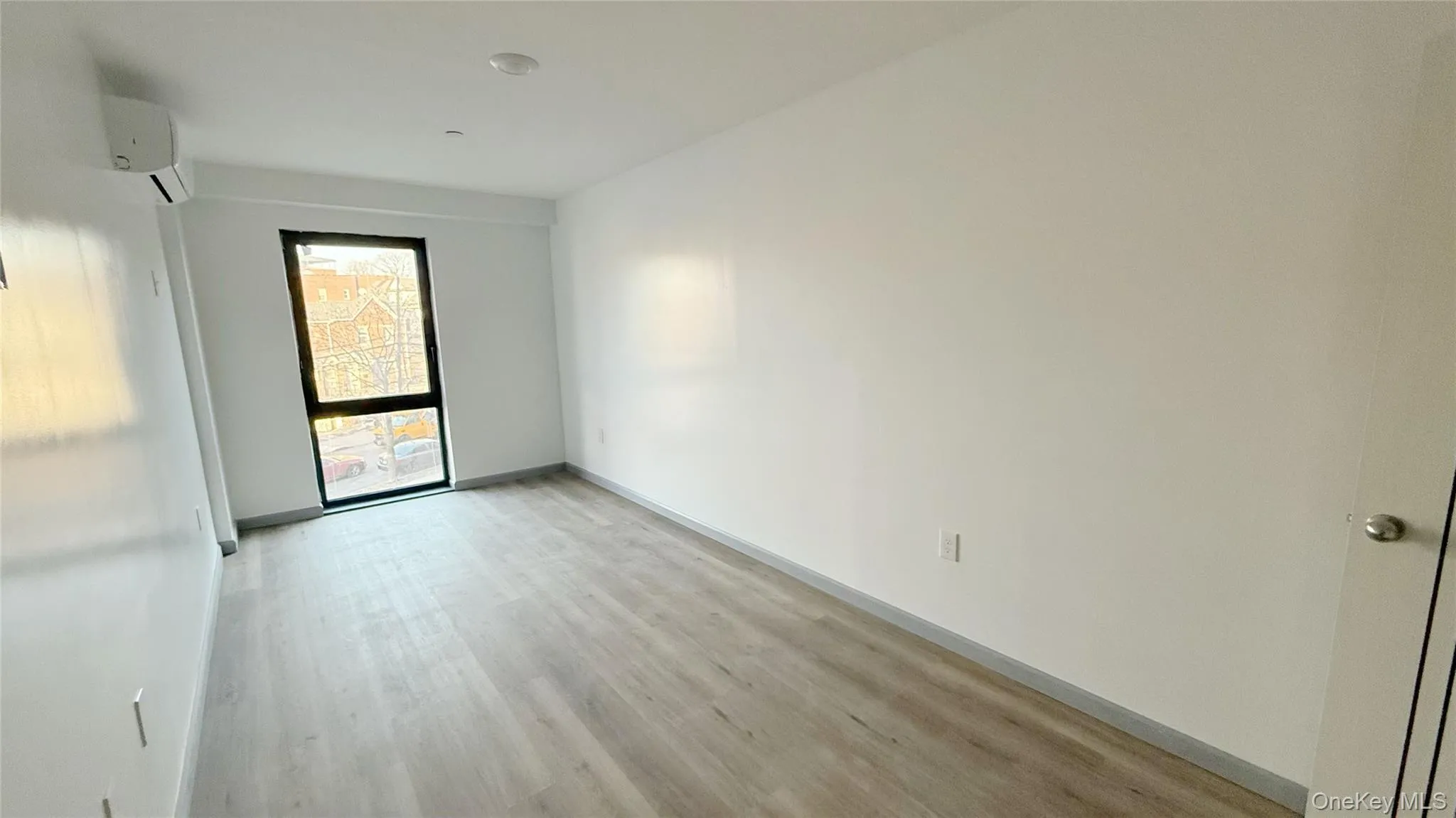 Unfurnished room with light wood finished floors and a wall mounted air conditioner Unfurnished room with light wood finished floors and a wall mounted air conditioner