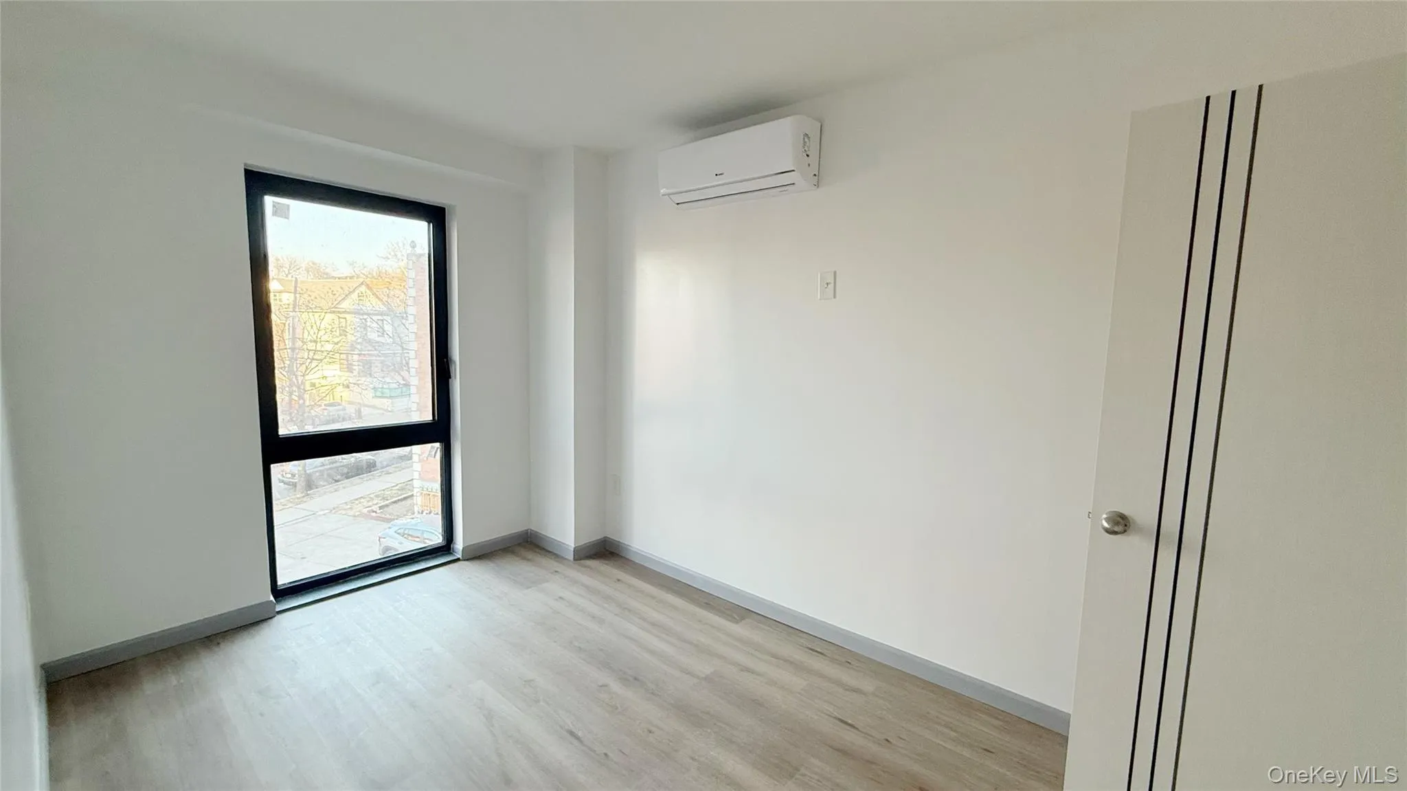 Spare room featuring light wood-type flooring and a wall mounted air conditioner Spare room featuring light wood-type flooring and a wall mounted air conditioner