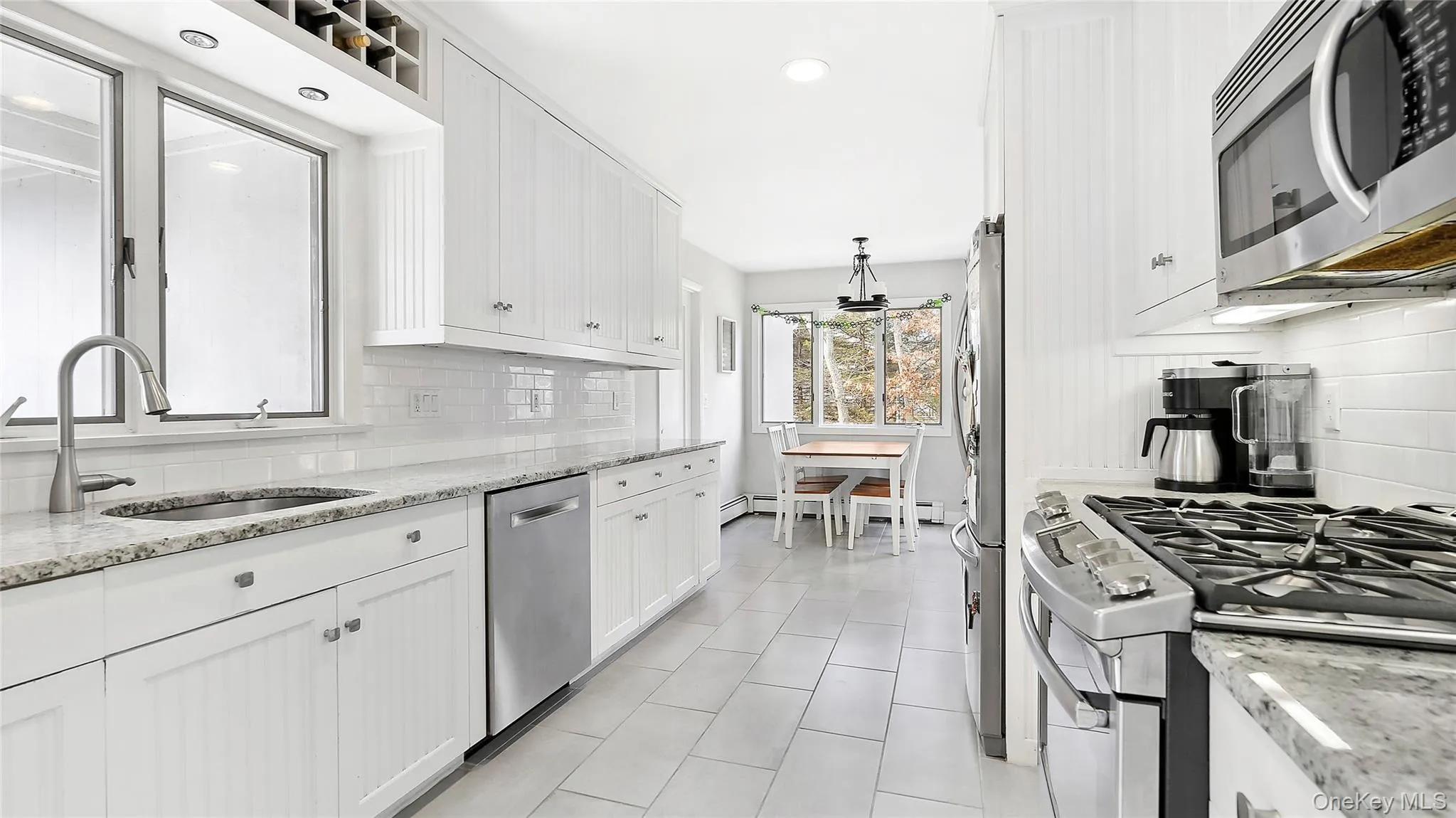 Kitchen with appliances with stainless steel finishes, white cabinets, backsplash, light stone countertops, and recessed lighting Kitchen with appliances with stainless steel finishes, white cabinets, backsplash, light stone countertops, and recessed lighting