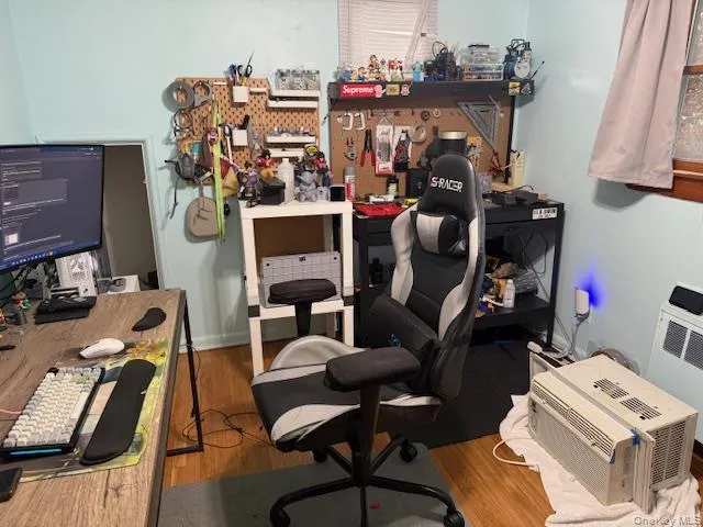 Office area featuring a workshop area, wood finished floors, and heating unit Office area featuring a workshop area, wood finished floors, and heating unit