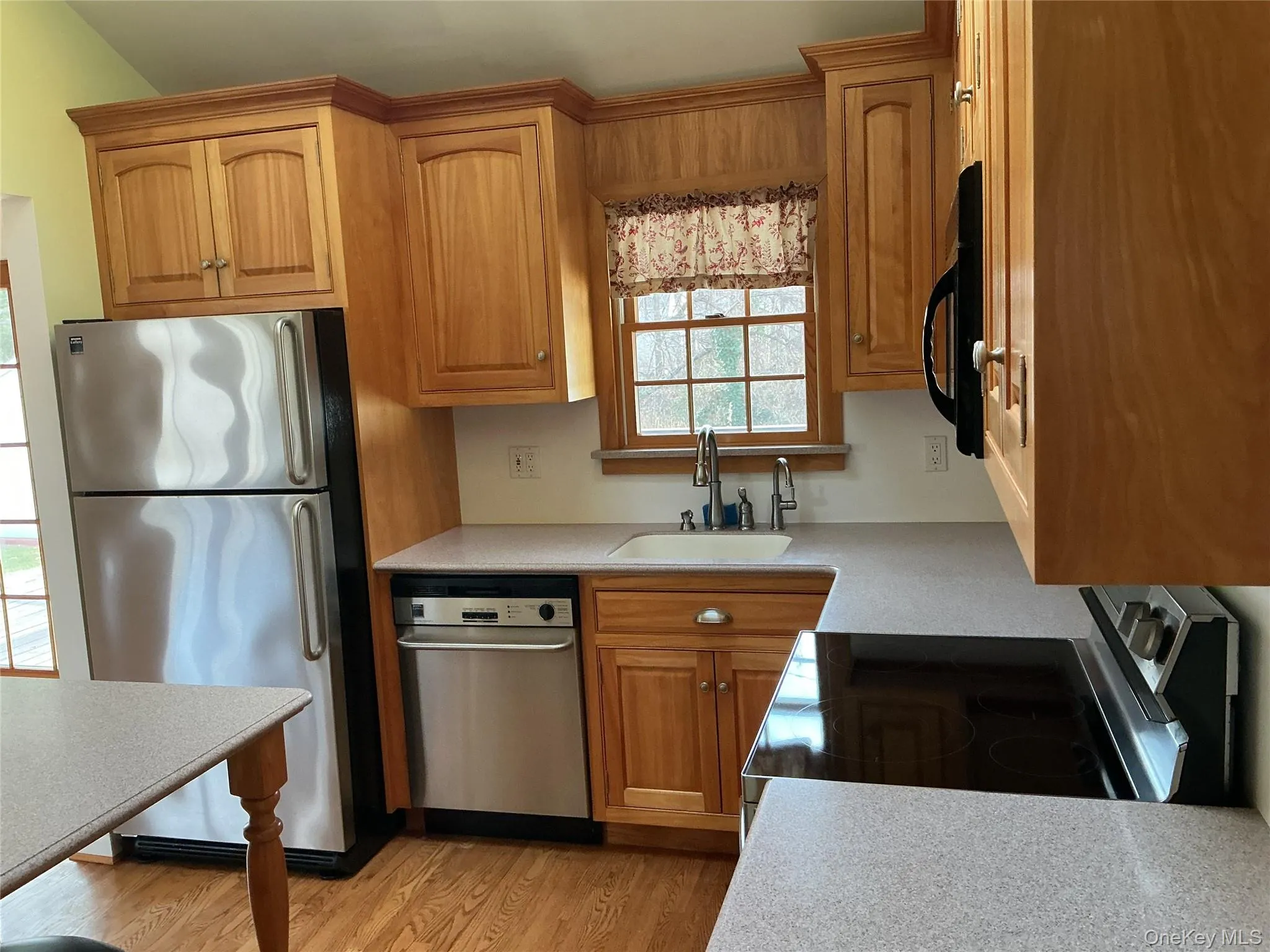Kitchen with stainless steel appliances, brown cabinets, and light wood finished floors Kitchen with stainless steel appliances, brown cabinets, and light wood finished floors