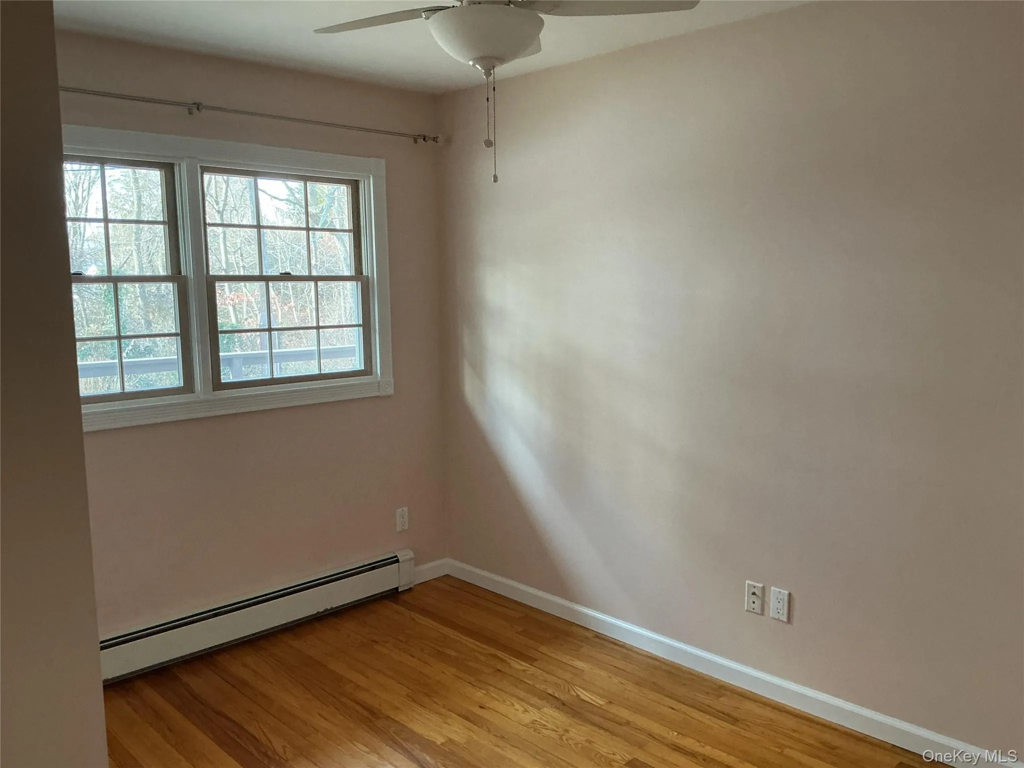 Unfurnished room with a baseboard heating unit, a ceiling fan, and light wood-style flooring Unfurnished room with a baseboard heating unit, a ceiling fan, and light wood-style flooring