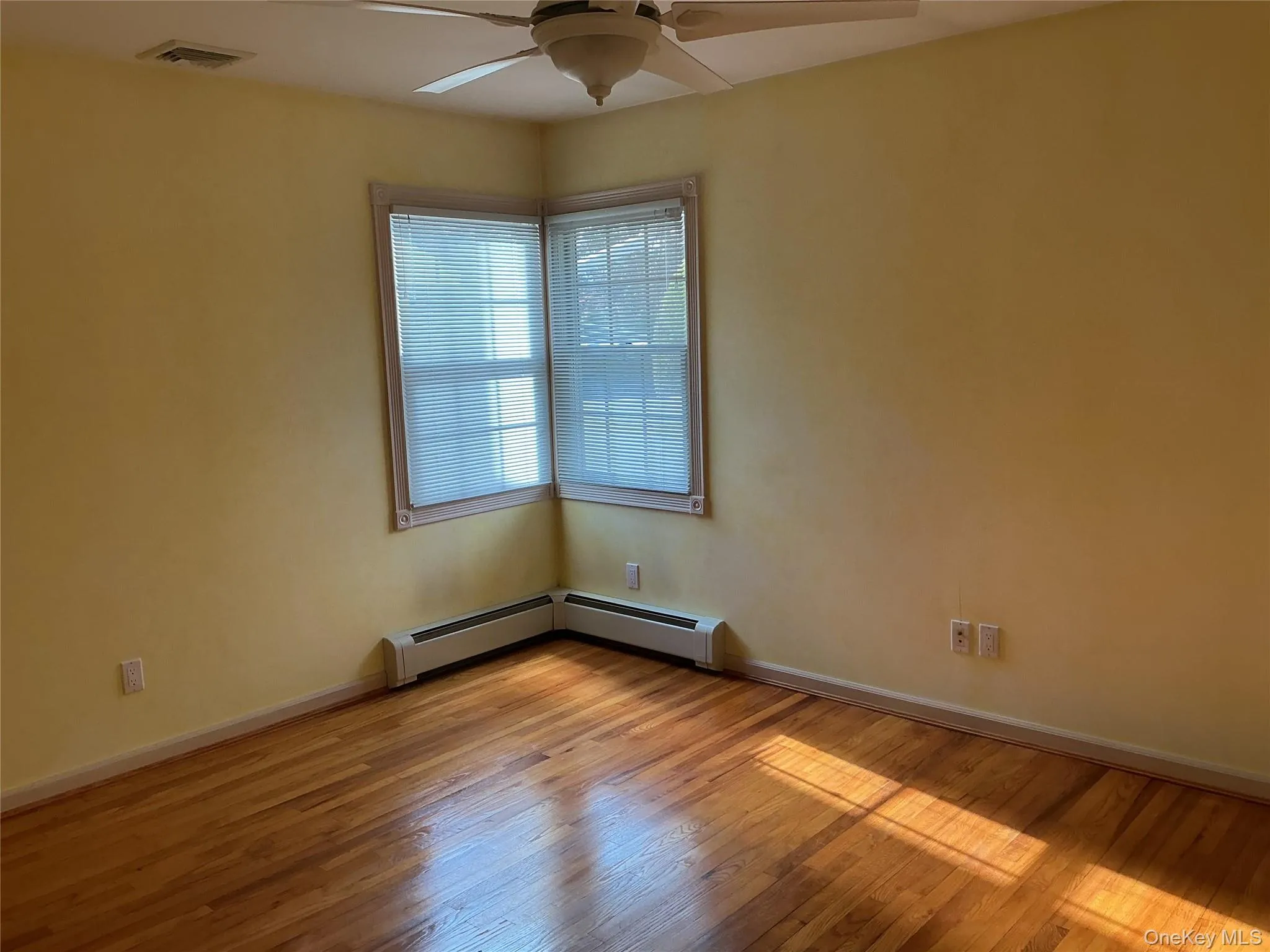Spare room with light wood-type flooring, ceiling fan, and baseboard heating Spare room with light wood-type flooring, ceiling fan, and baseboard heating