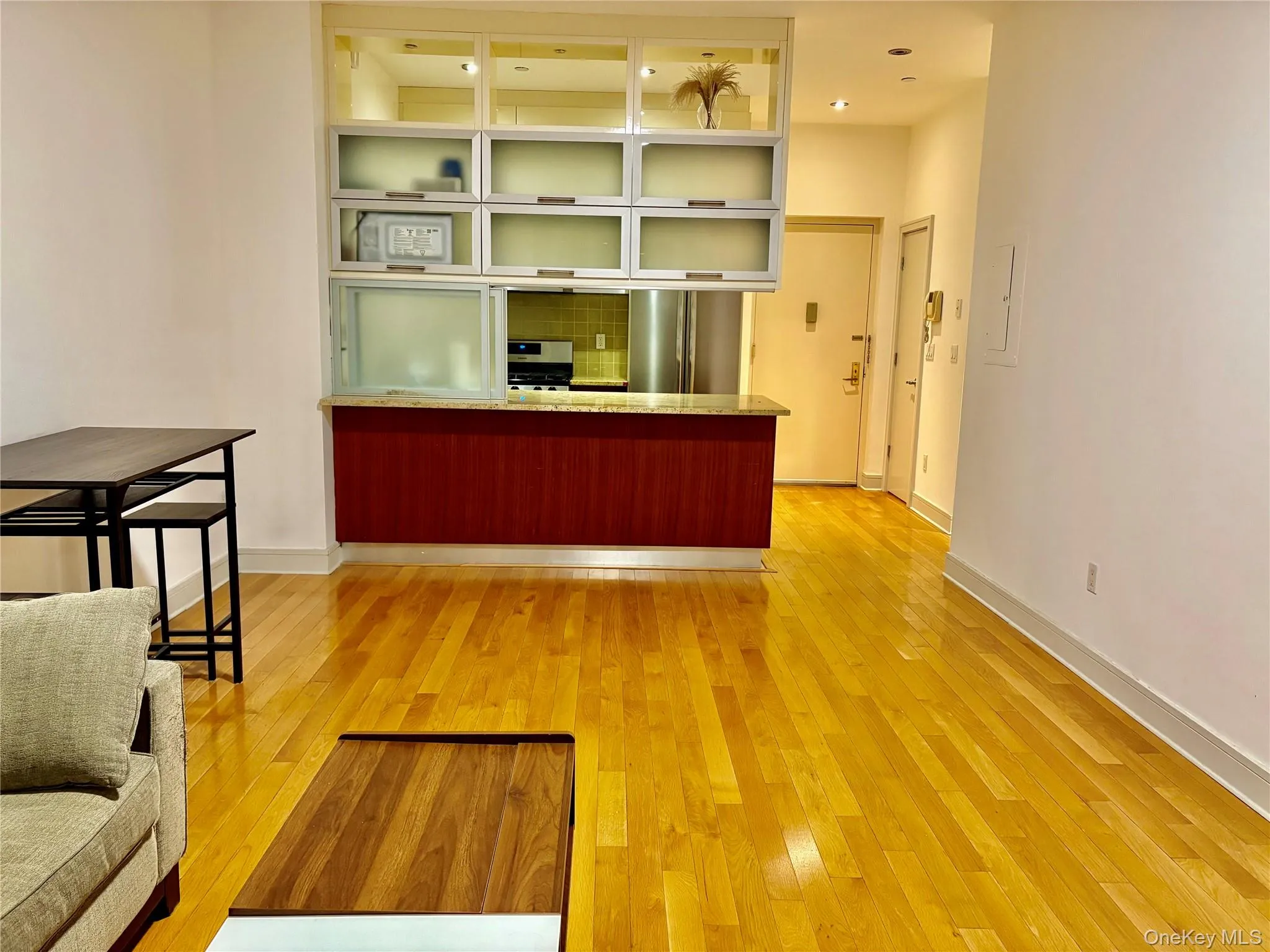 Kitchen with a peninsula, light wood-type flooring, stainless steel appliances, light stone counters, and glass insert cabinets Kitchen with a peninsula, light wood-type flooring, stainless steel appliances, light stone counters, and glass insert cabinets