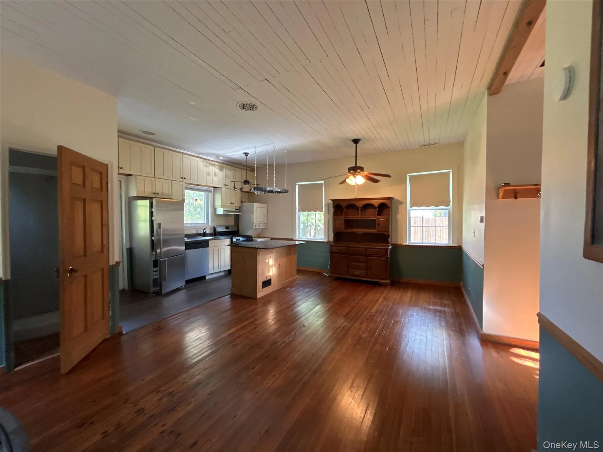 Kitchen with stainless steel appliances, dark wood finished floors, a center island, wood ceiling, and dark countertops Kitchen with stainless steel appliances, dark wood finished floors, a center island, wood ceiling, and dark countertops