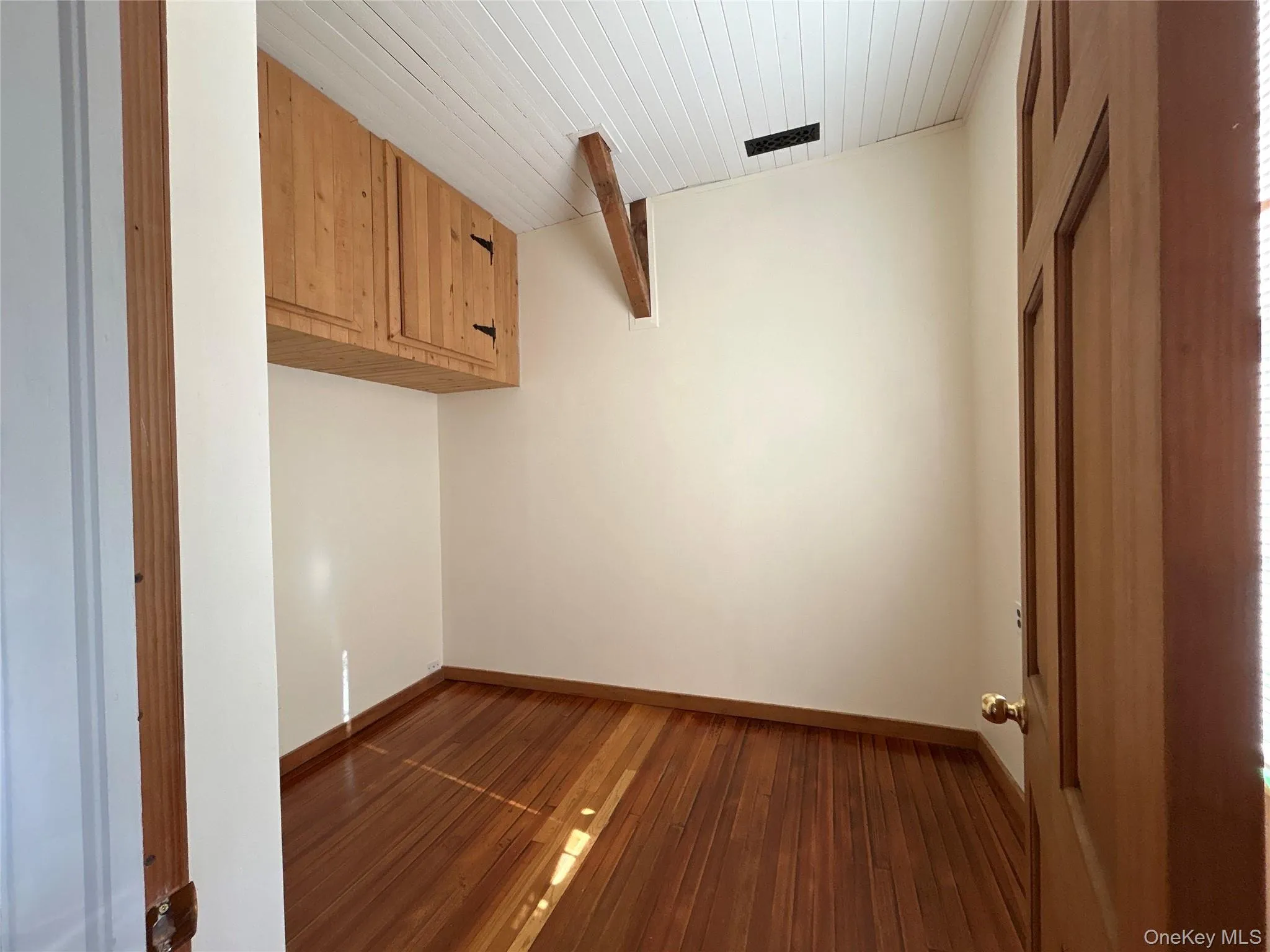 Unfurnished room with dark wood-type flooring and a wooden ceiling with exposed beams Unfurnished room with dark wood-type flooring and a wooden ceiling with exposed beams