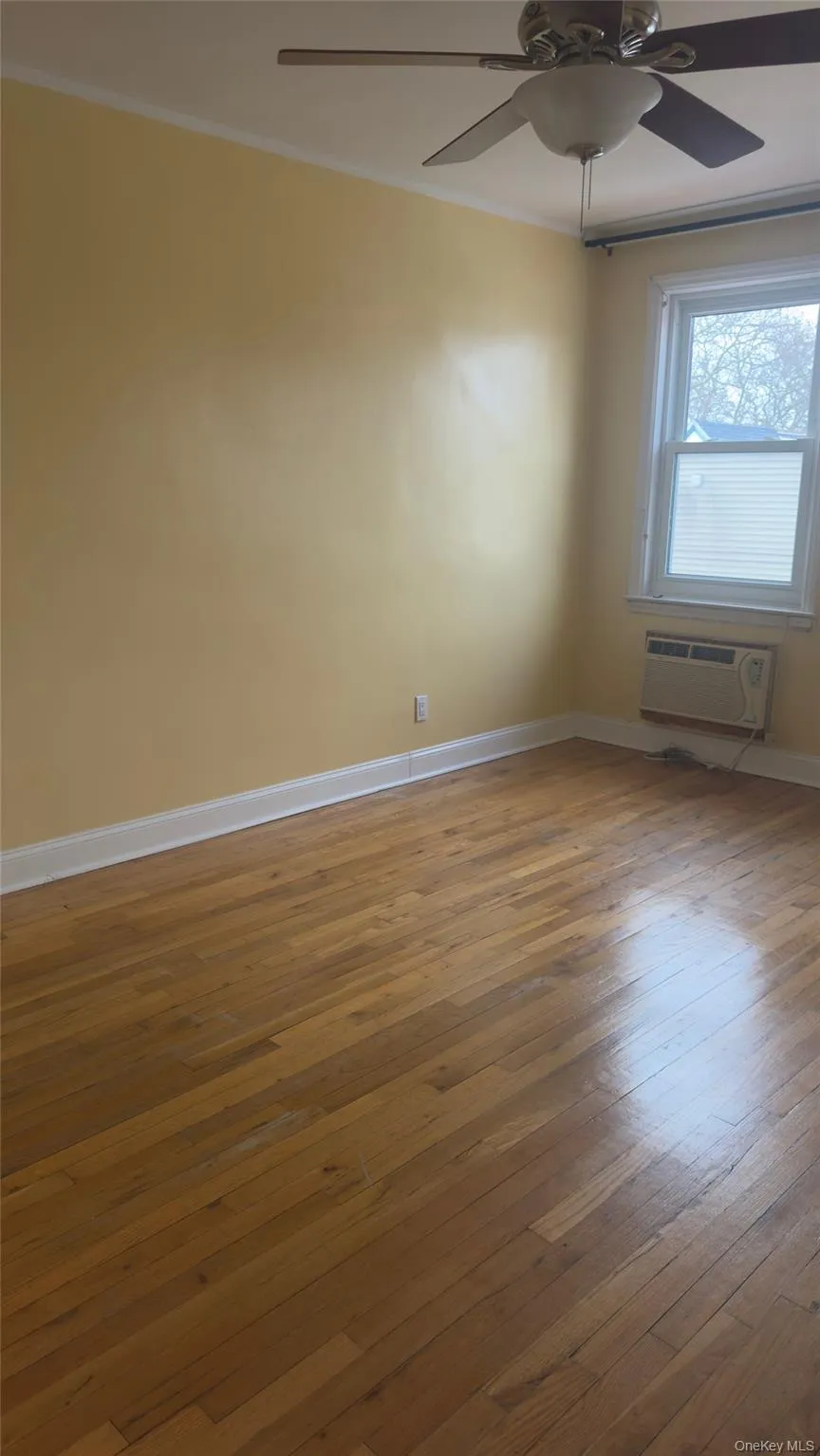 Unfurnished room with hardwood / wood-style flooring, ornamental molding, and a ceiling fan Unfurnished room with hardwood / wood-style flooring, ornamental molding, and a ceiling fan
