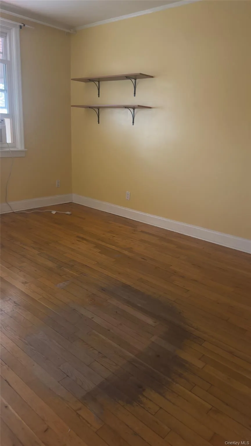 Empty room with dark wood-style flooring and ornamental molding Empty room with dark wood-style flooring and ornamental molding