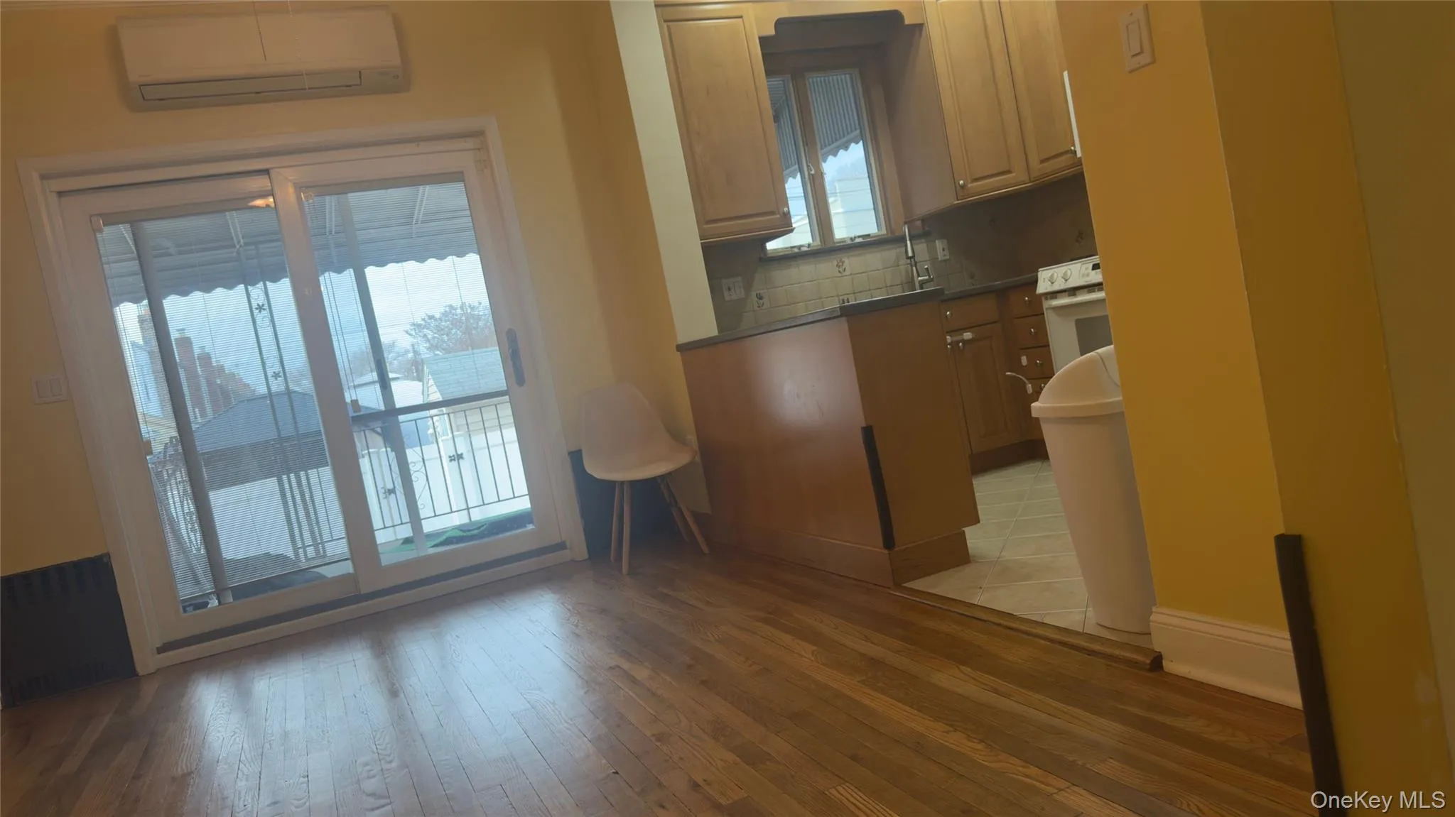 Kitchen with dark countertops, an AC wall unit, brown cabinets, radiator heating unit, and light wood-style floors Kitchen with dark countertops, an AC wall unit, brown cabinets, radiator heating unit, and light wood-style floors