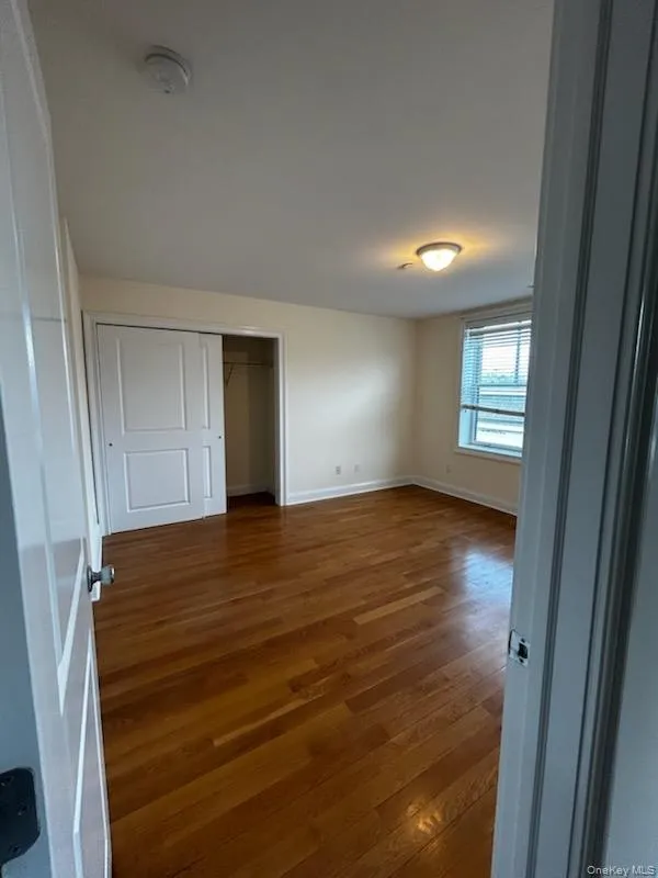 Unfurnished bedroom with dark wood-style floors and a closet Unfurnished bedroom with dark wood-style floors and a closet