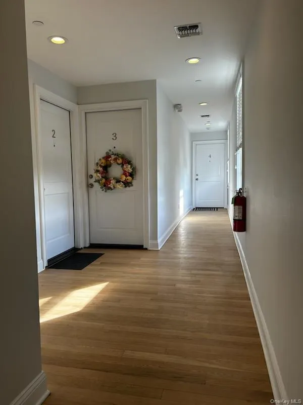 Hallway with recessed lighting and light wood-type flooring Hallway with recessed lighting and light wood-type flooring