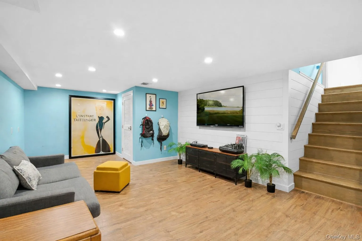 Finished Lower Level featuring stairs, recessed lighting, light wood-style flooring, wooden walls, and an accent wall Finished Lower Level featuring stairs, recessed lighting, light wood-style flooring, wooden walls, and an accent wall
